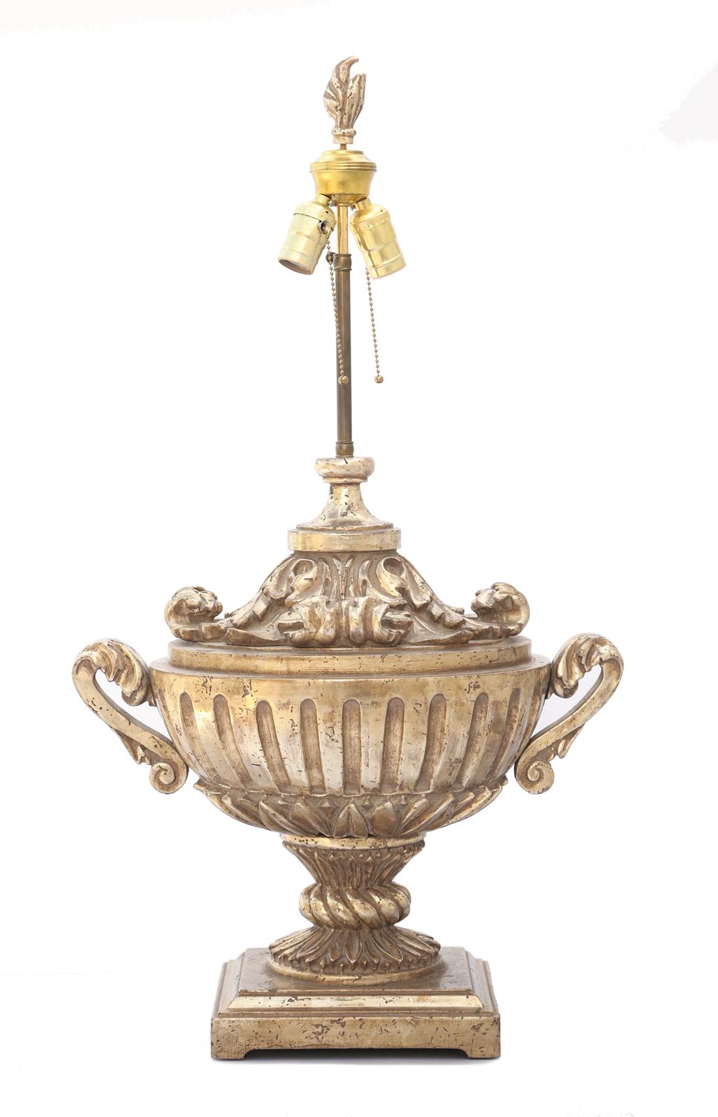 Single lamp, of silver giltwood, hand-carved into a campana urn of sold wood; the ovoid, fluted body flanked by S-scroll handles, seated on a foliate cup, its hourglass neck wrapped with a large carved braid, to its graduated, square plinth, capped