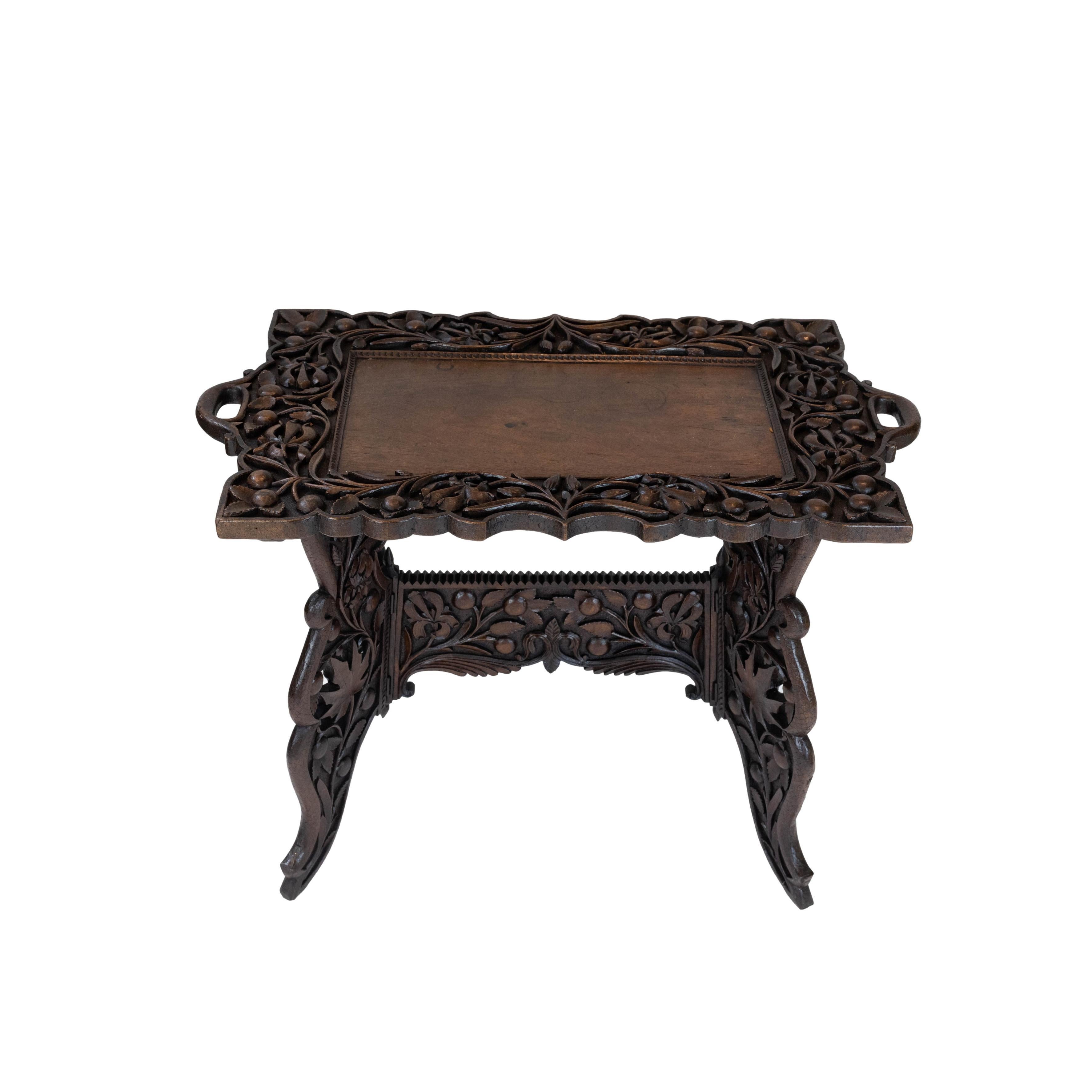 Elaborately hand-carved solid walnut campaign tray-top table, English, ca. 1890, with naturalistically carved cherries and leaves, either side with filigreed maple leaves. Originally made as a collapsable campaign piece, the frame and top are now