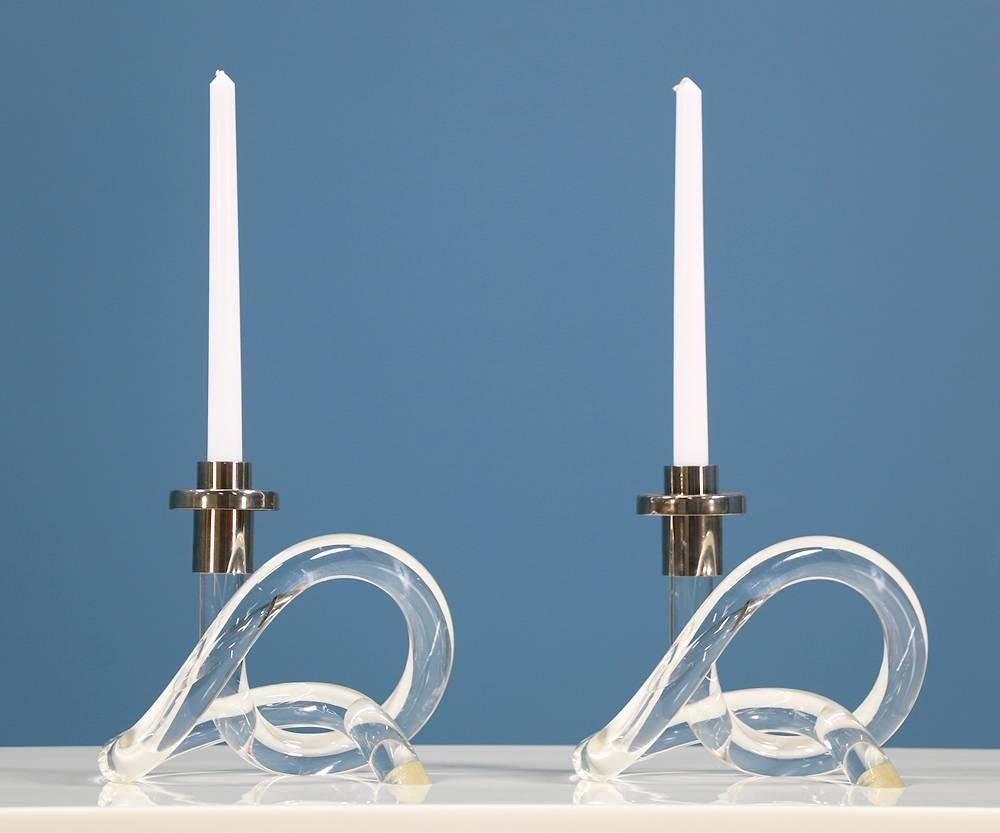A pair of Mid Century Modern Lucite Pretzel Candle Holders designed by Elaine Bscheider for Dorothy Thorpe in the United States circa 1970’s. This sculptural candelabra design features a pretzel-like body made of lucite capped with a chromed metal