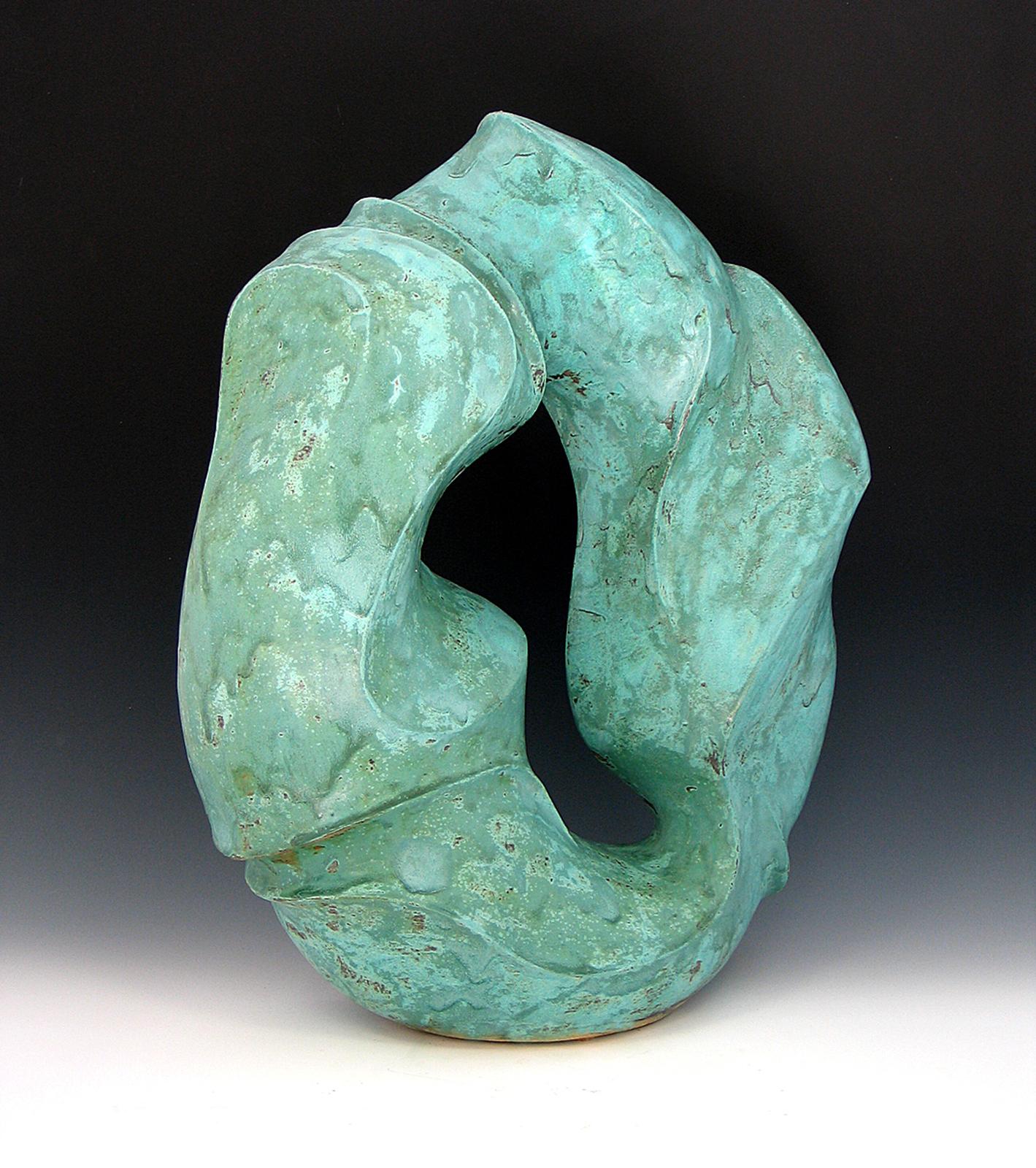 “Water’s Way”, bright aqua  ceramic with swirling marks, displays flowing movement of water in shape and surface. Always looking for new materials and methods, the artist has made sculpture in such diverse materials as wood, metal, concrete,