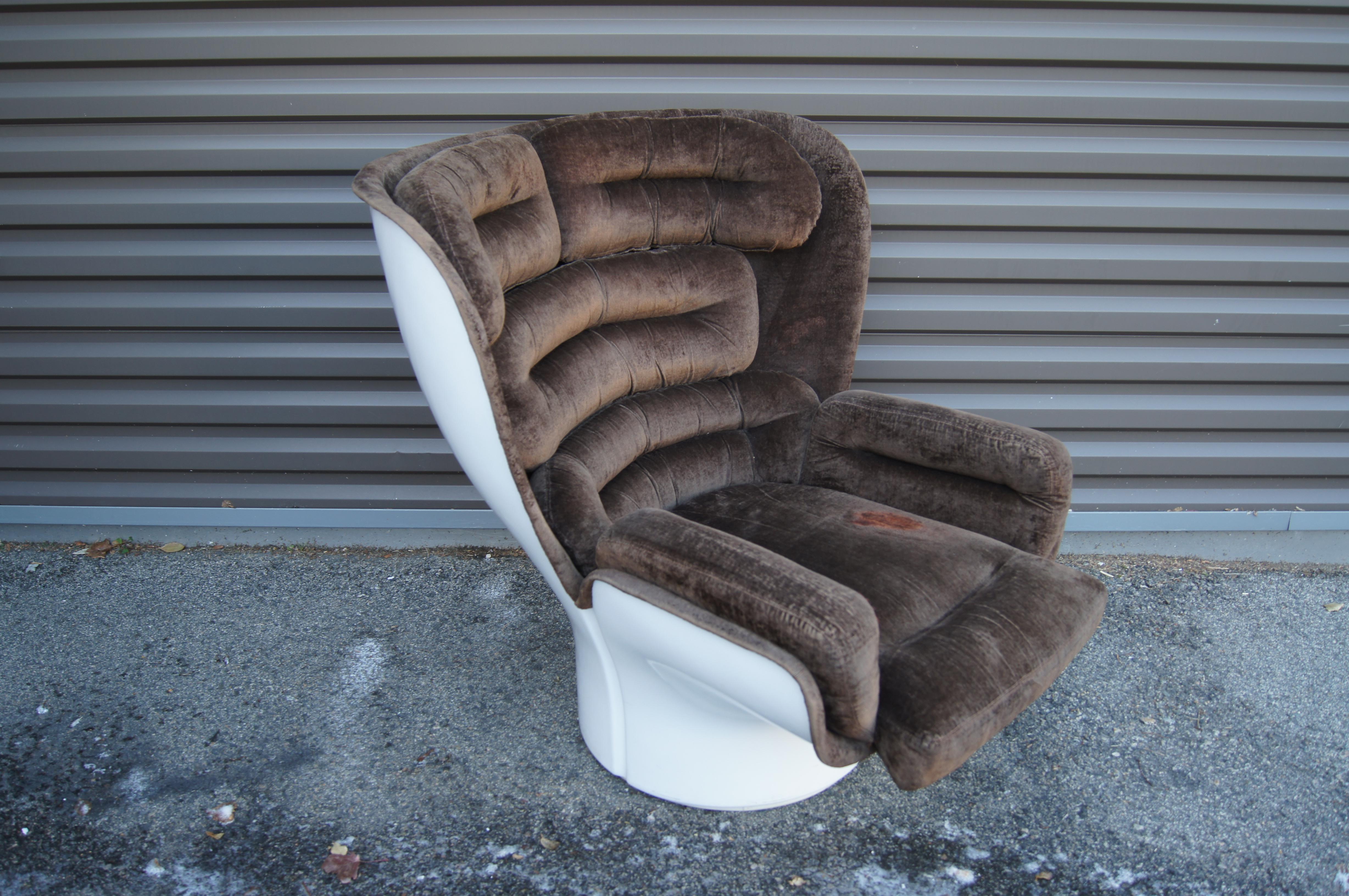 Der ikonische Elda Chair wurde 1965 von Joe Colombo entworfen (und nach seiner Frau benannt). Er verbindet einen kräftigen Space-Age-Rahmen aus Fiberglas mit tiefen, kanalisierten Kissen (insgesamt sieben abnehmbare), die den Sitzenden in eine