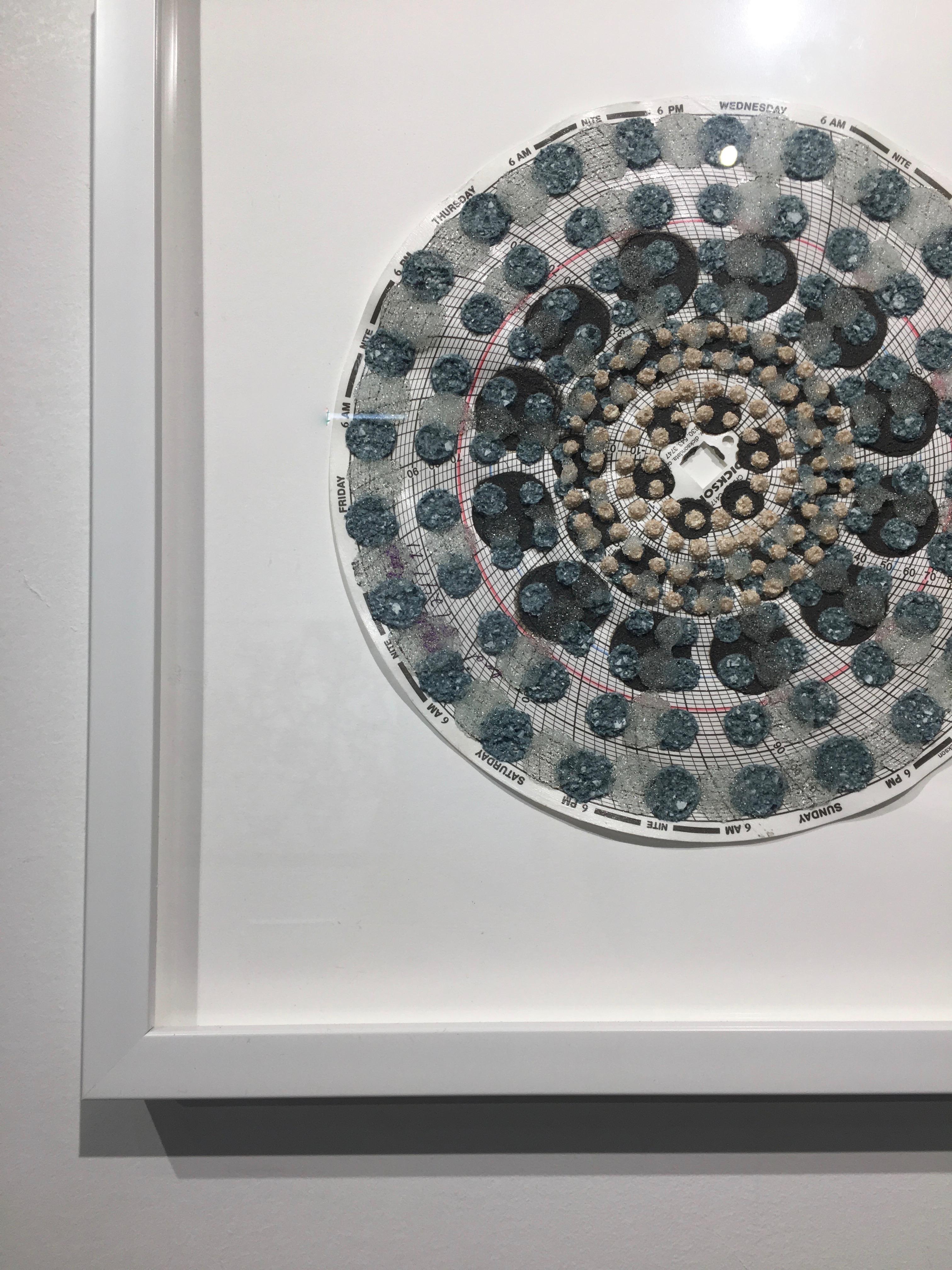 In this contemporary mixed media mandala, carefully applied layers of wood ash, chicken eggshell, emu eggshell, glass beads, and polymer medium on hygrothermogaph paper create surface texture in intricate patterns in an ordered, symmetrical,