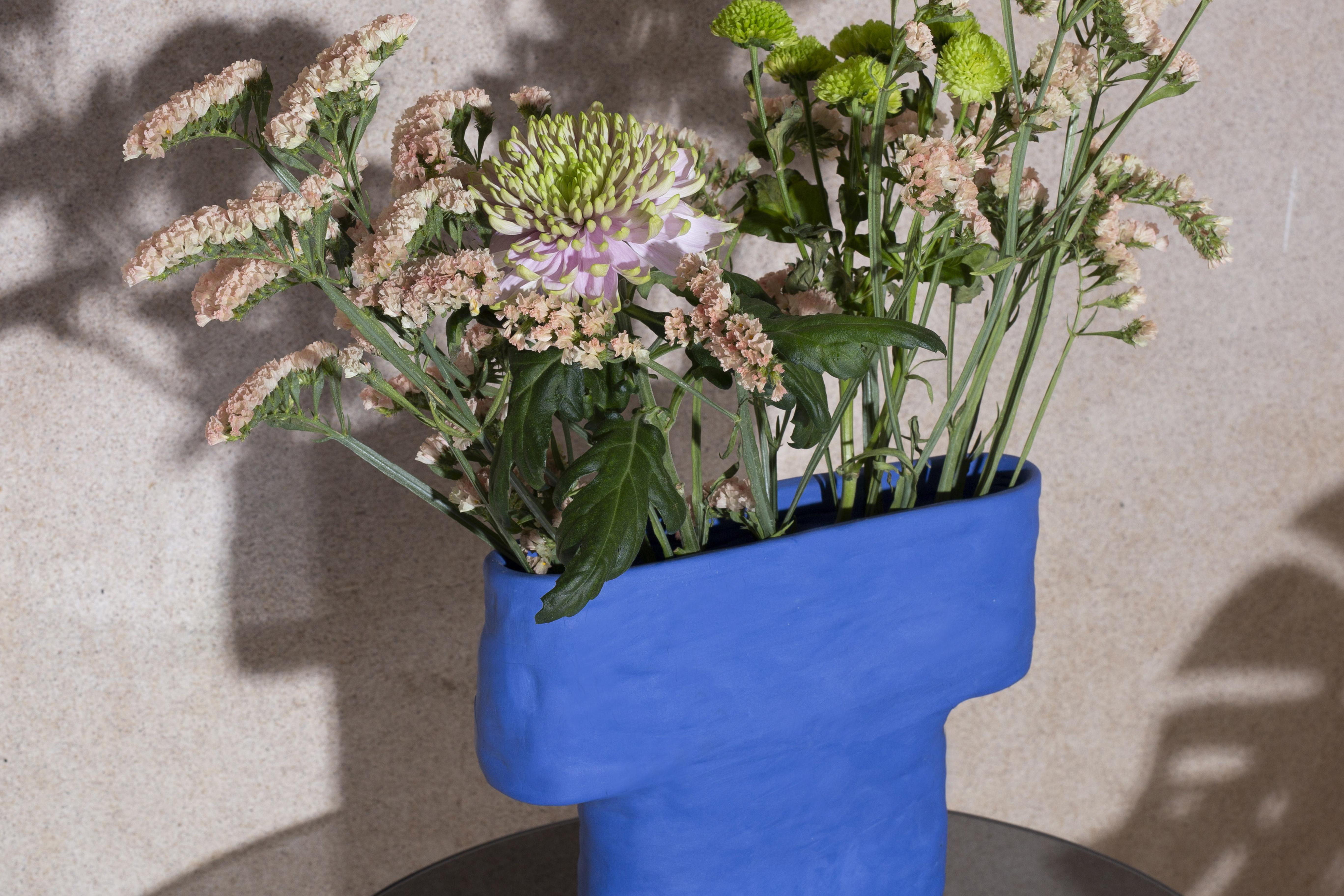 Pillar-vase takes inspiration from the ancient human-made rock formations. It references the ancient architecture and the human touch in carved stones. The sculptural vase displays flowers in a horizontal fan-like alignment and the electric blue
