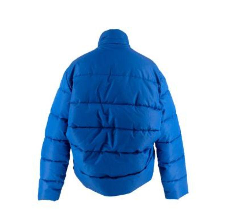 Giacca Puffer Balenciaga blu elettrico
 
 - Esterno blu elettrico vibrante, interno nero
 - Generosamente imbottito
 - Collo a imbuto
 - Passaggio attraverso la cerniera 
 - Logo sul petto
 - Tasche laterali inserite
 - Forma a trapezio
 
 I