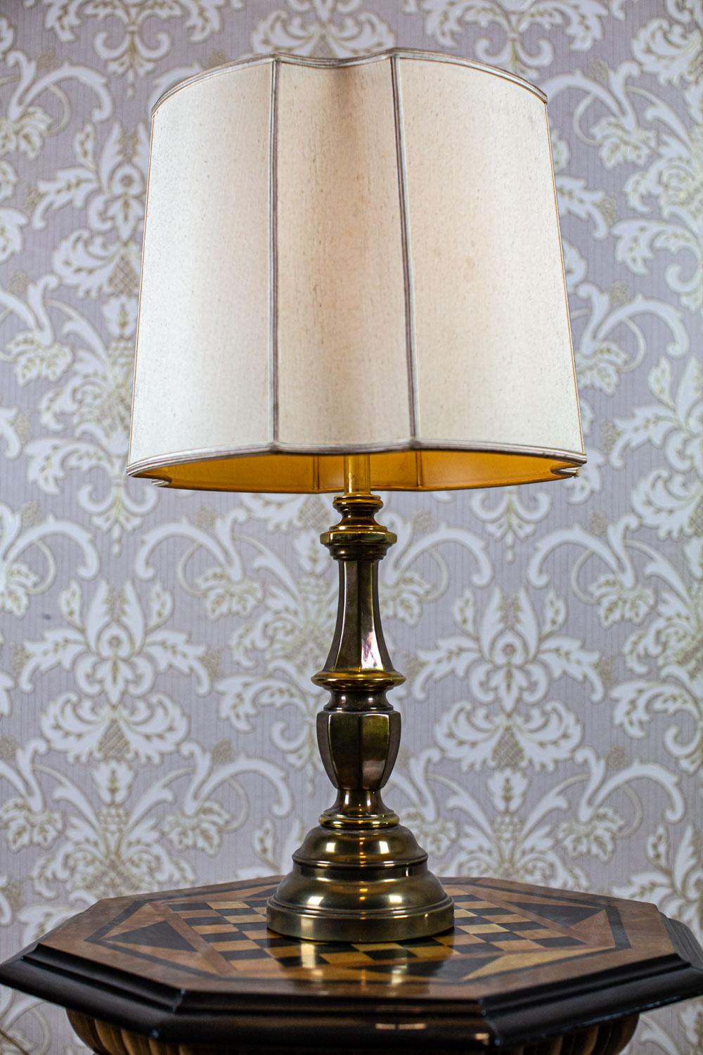 Electric Table Lamp from the 20th Century on Metal Base

We present you this electric table lamp from the 2nd half of the 20th century.
The base is made of metal, whereas the shade of a fabric with a wavy trim.
There is a single E27 light bulb