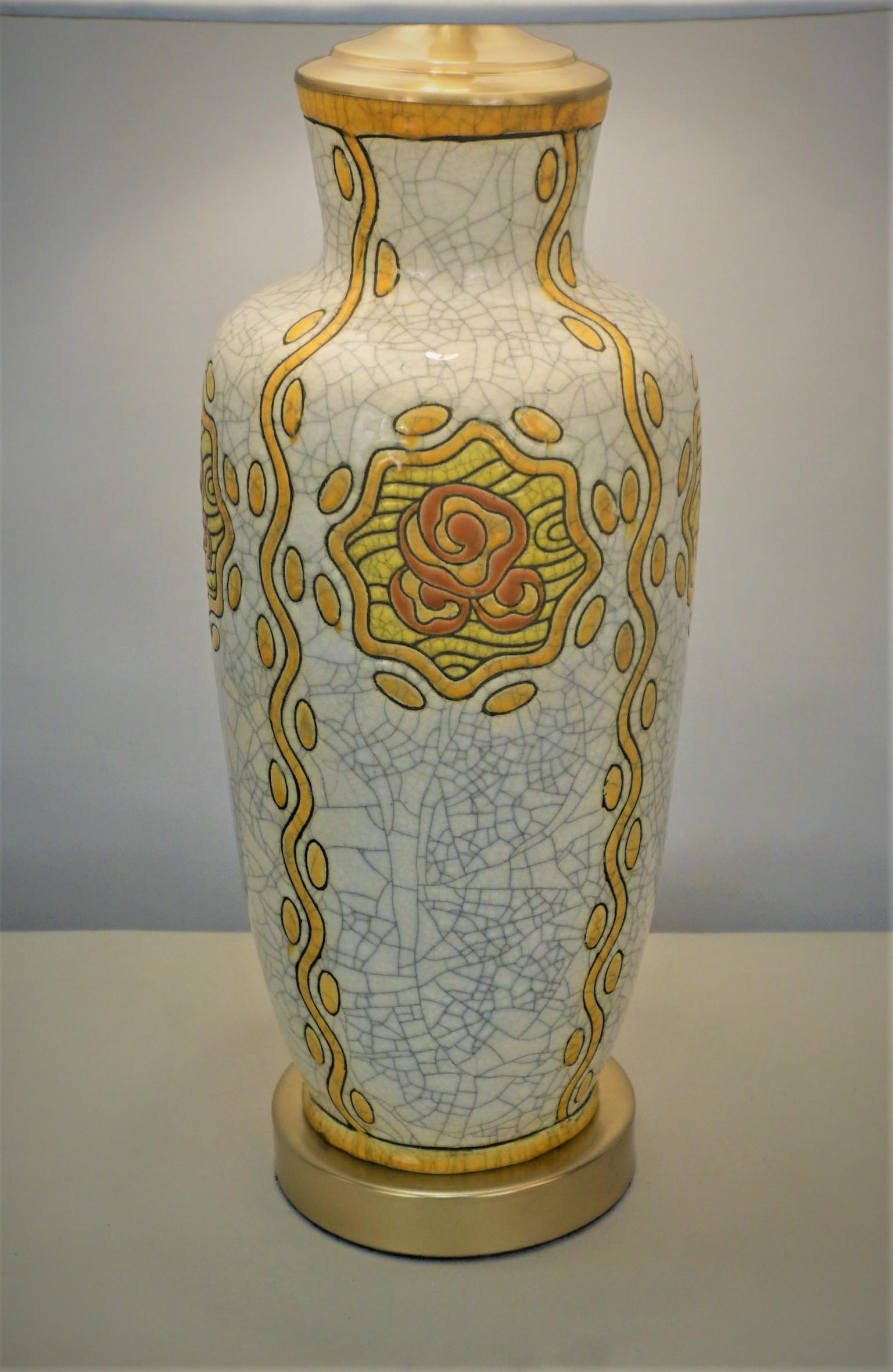 Poterie émaillée décorée de fleurs jaunes stylisées sur fond de craquelins blanc cassé qui a été transformée par un professionnel en lampe de table.