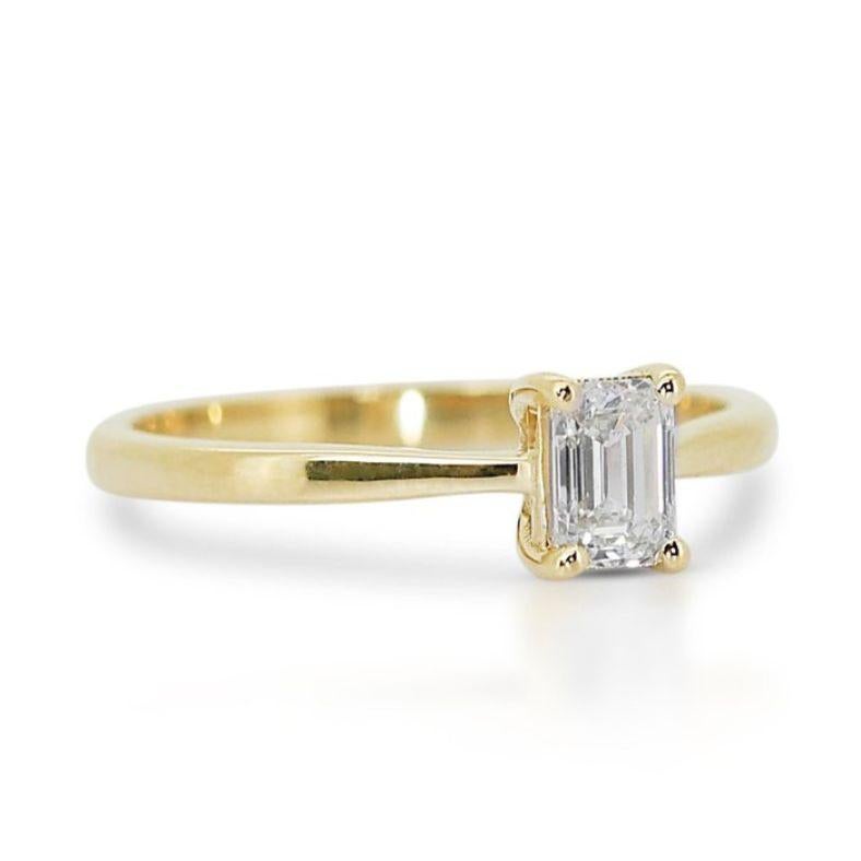 Libérez votre rayonnement intérieur avec cette captivante bague à diamant émeraude, dotée d'une pierre centrale de 0,9 carat qui exsude une sophistication intemporelle. Réalisée en or jaune 18 carats, cette pièce exquise est méticuleusement polie à