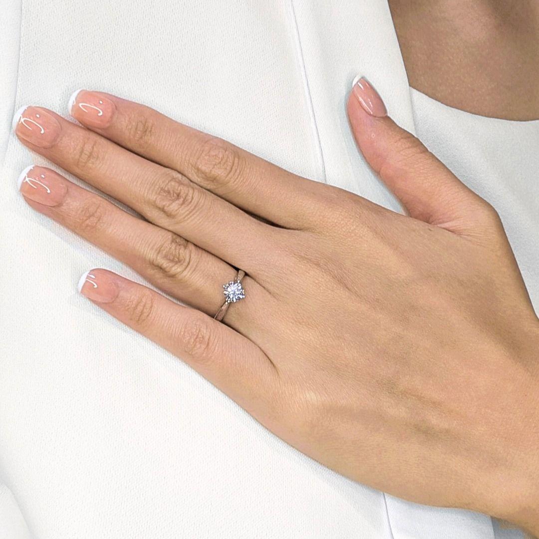 Simbolo classico di eleganza e devozione, questo anello solitario è caratterizzato da uno splendido diamante naturale rotondo da 0,90 carati con taglio a brillante (colore G, purezza VS2) incastonato in una raffinata montatura a quattro punte che