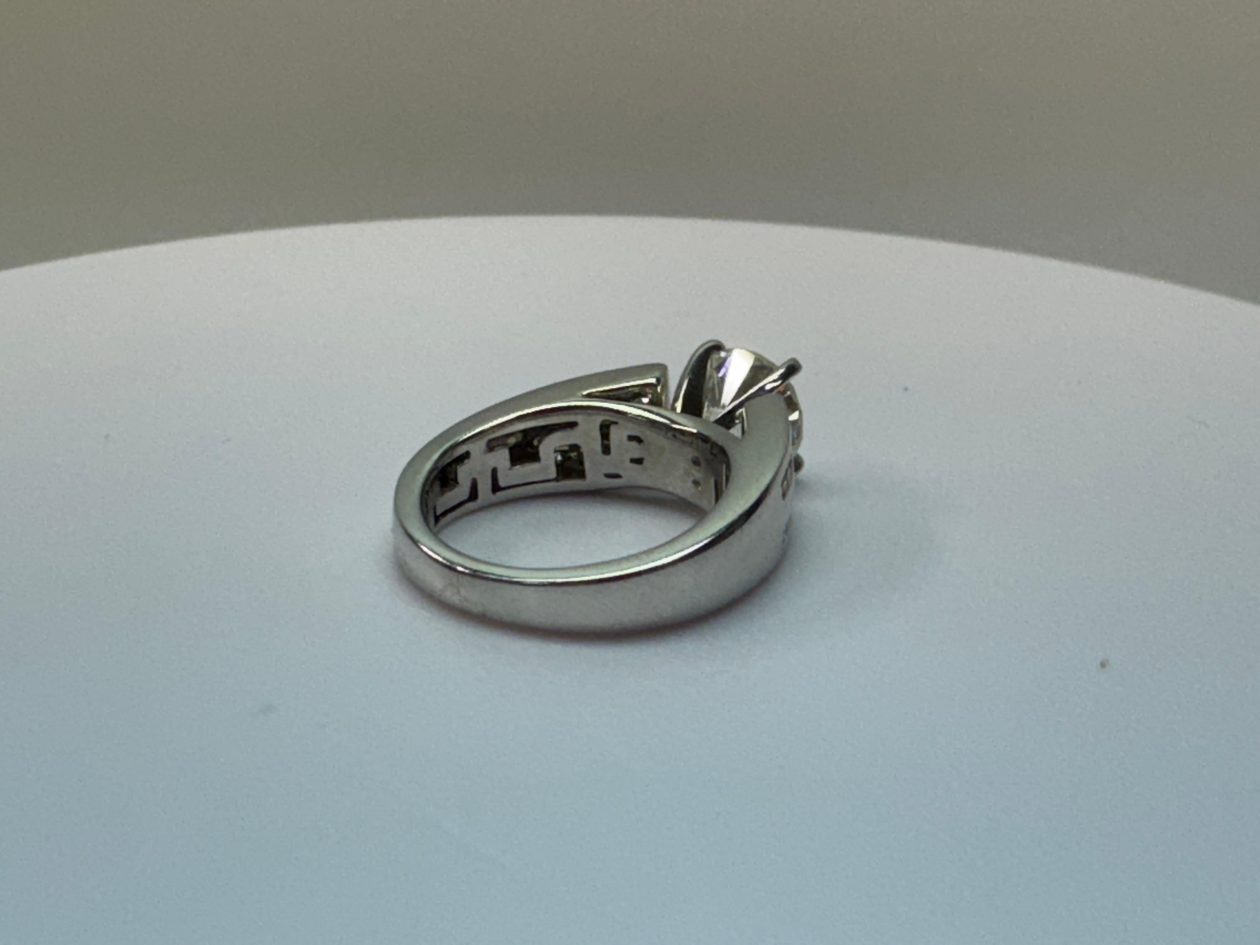 One 14k White Gold Diamond ring with raised and centered round brilliant secured in a 4-prong head. This diamond is accented with 20 small round brilliant cut diamonds that are channel set in 2 rows on the ring's cathedral-styled shoulders. The