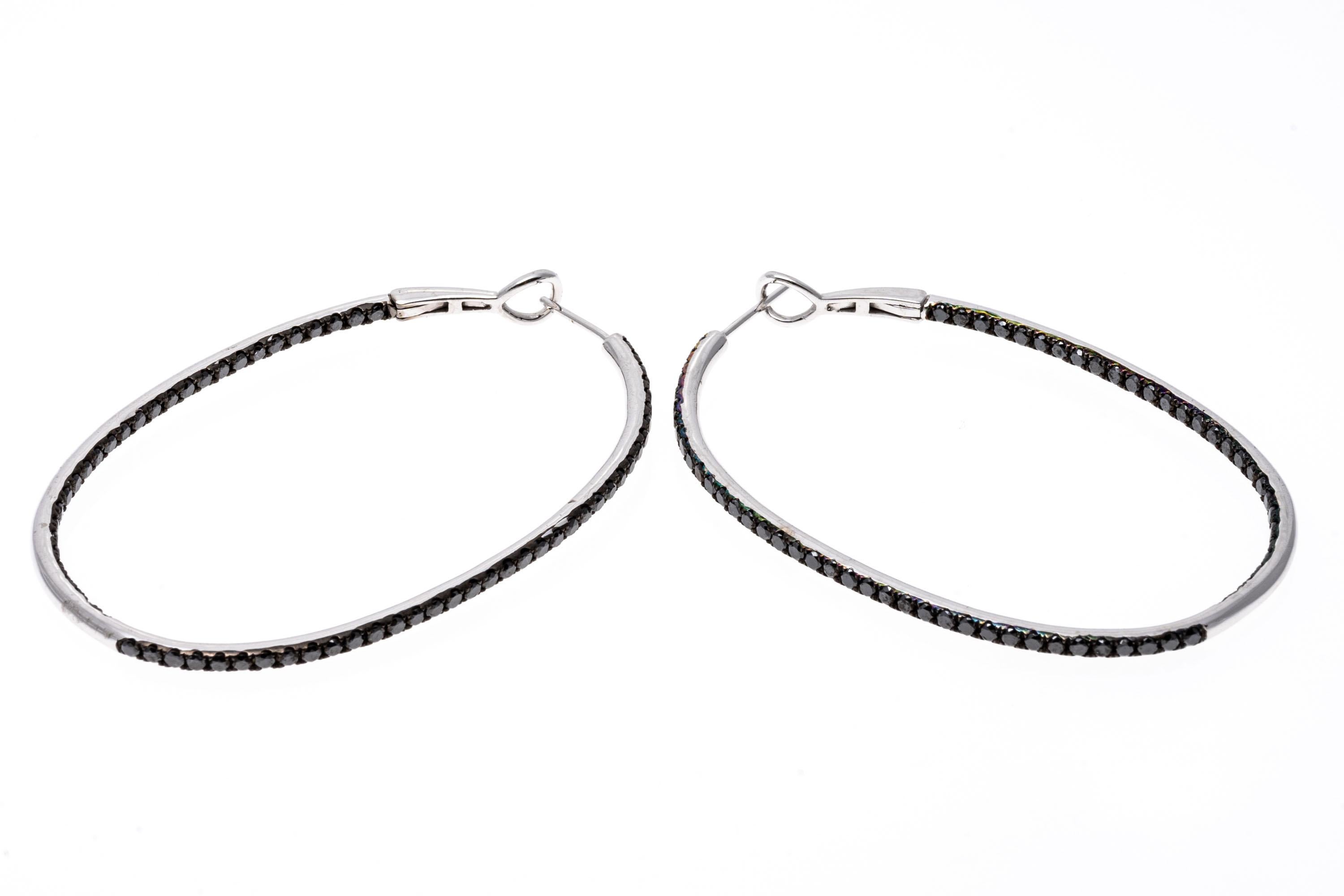 These graceful elongated hoop earrings are crafted of 14K white gold.  Black diamonds trail over the face of the earrings as well as over the inside. The diamonds are approximately 3.4 TCW. Post and leaver backings.
Marks: 14K 585
Dimensions: 2 1/4