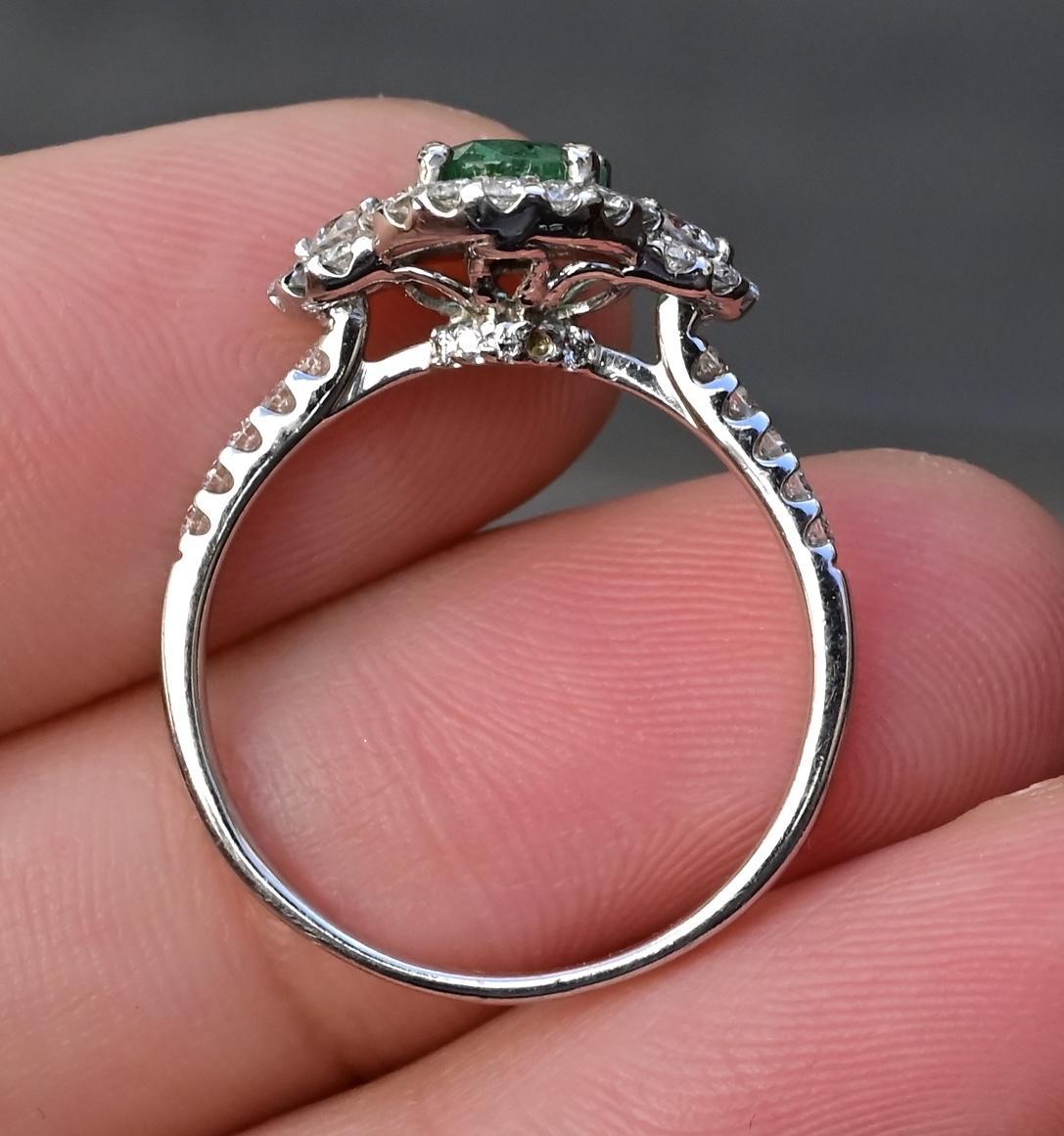 This sophisticated 14K white gold ring showcases a stunning 1.00 carat emerald, radiating a rich green color. The emerald is complemented by .45 carats of sparkling diamonds, ranging from VS to SI clarity, adding brilliance and contrast to the