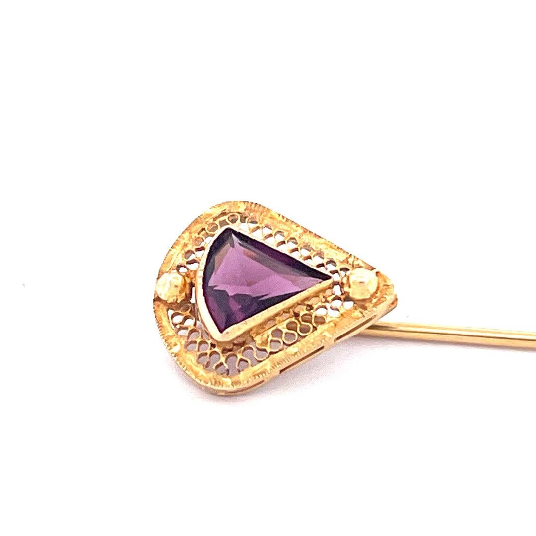 Indulge in the exquisite beauty of this elegant 14k yellow gold amethyst fan shape pin. The pin has stunning amethyst stone meticulously carved into a graceful fan shape, accentuated by intricate carvings surrounding it. Weighing 1.4g, this pin is