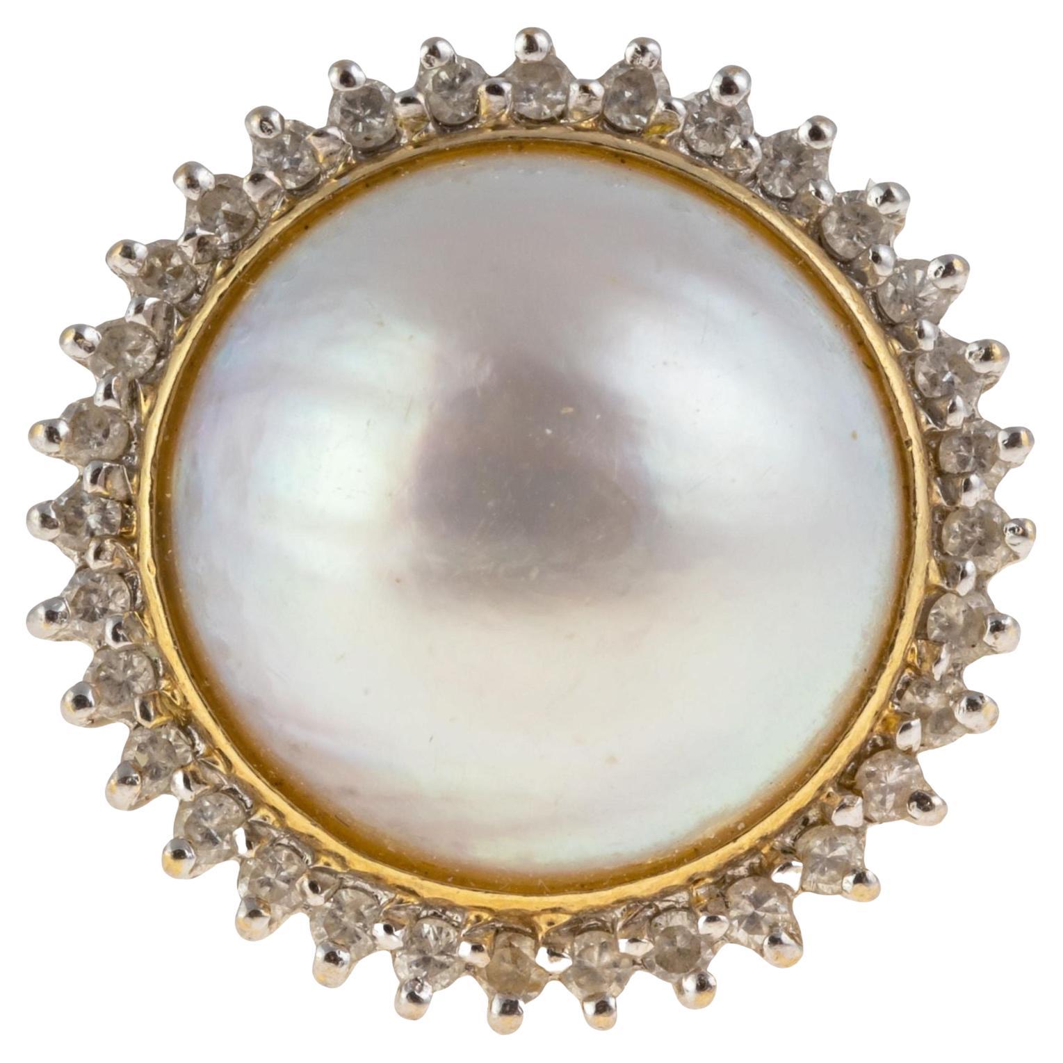 Elegant 14K Yellow Gold Mabe Pearl Diamond Ring
Vintage Italian classic large mabe pearl ring crafted of 14k gold features a central 14mm mabe pearl surrounded by a halo of small diamonds. Size 7. Weight approximately 7.7 grams. Marked 14kG and 585.