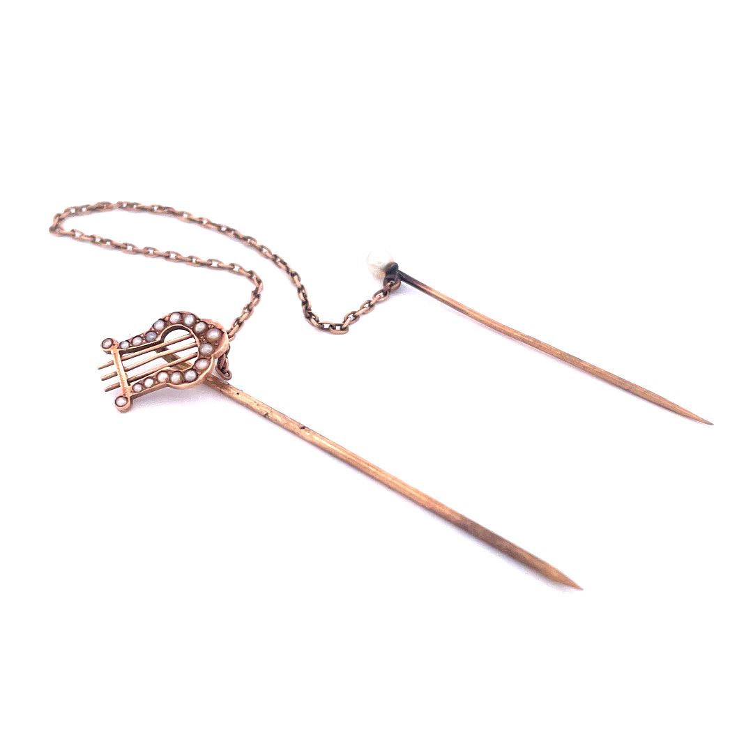 Enhance your ensemble with the elegant allure of this 14k yellow gold pearl and chain pin.The pin features two beautifully connected pieces with a delicate chain. One pin showcases a decorative crown adorned with lustrous pearls, while the other pin