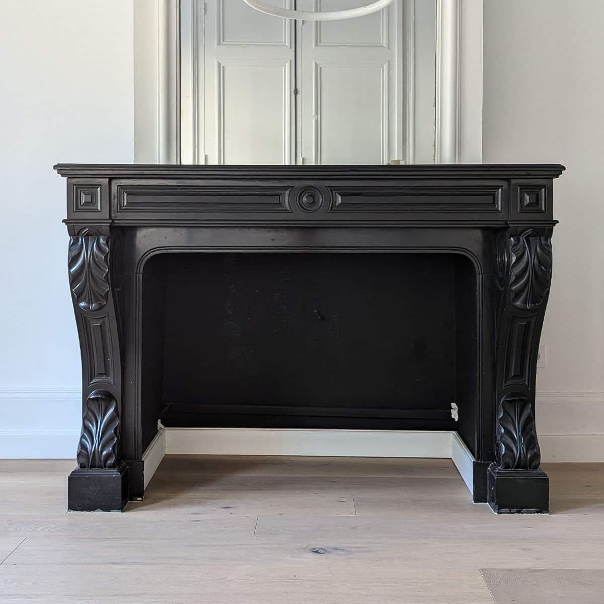 A striking mid-19th century fireplace mantel crafted from fine black Belgian marble, dating to the 1840s. This elegant architectural piece showcases classic proportions and intricate carvings, including bold acanthus leaves and volutes on the jambs,