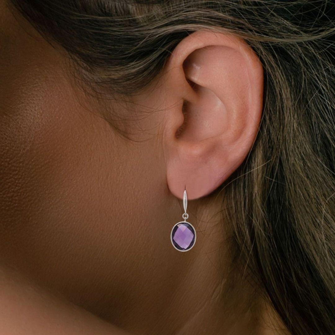 Adorn yourself with elegance and grace wearing these exquisite 18K white gold amethyst drop earrings. The earrings feature two alluring oval-shaped amethyst stones, each with a generous carat weight of 1.50ct, showcasing a captivating purple