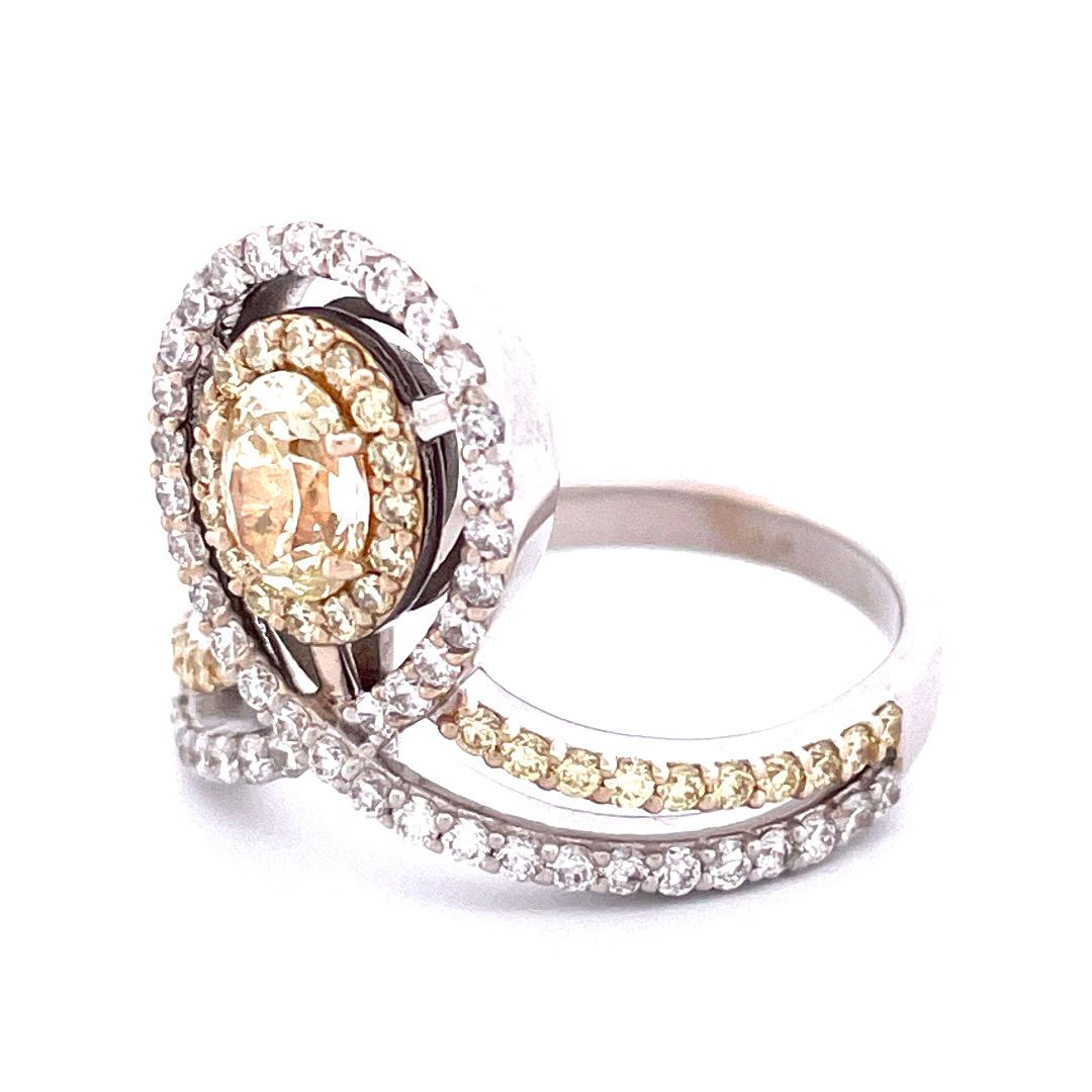 Strahlen Sie königliche Eleganz aus mit diesem exquisiten Ring aus 18-karätigem Weißgold mit einem fesselnden Kronendesign. In seinem Zentrum ruht ein atemberaubender gelber ovaler Diamant, umgeben von einer harmonischen Anordnung gelber und weißer