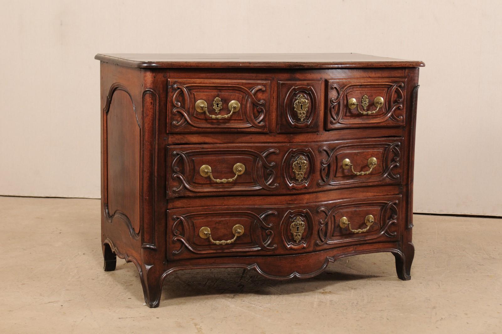 An elegant French Louis XV serpentine commode from the 18th century. This antique chest from France with curvy top and bowed front, features three drawers across the top facade, with two full-sized drawers beneath. The sides have fluidly-carved