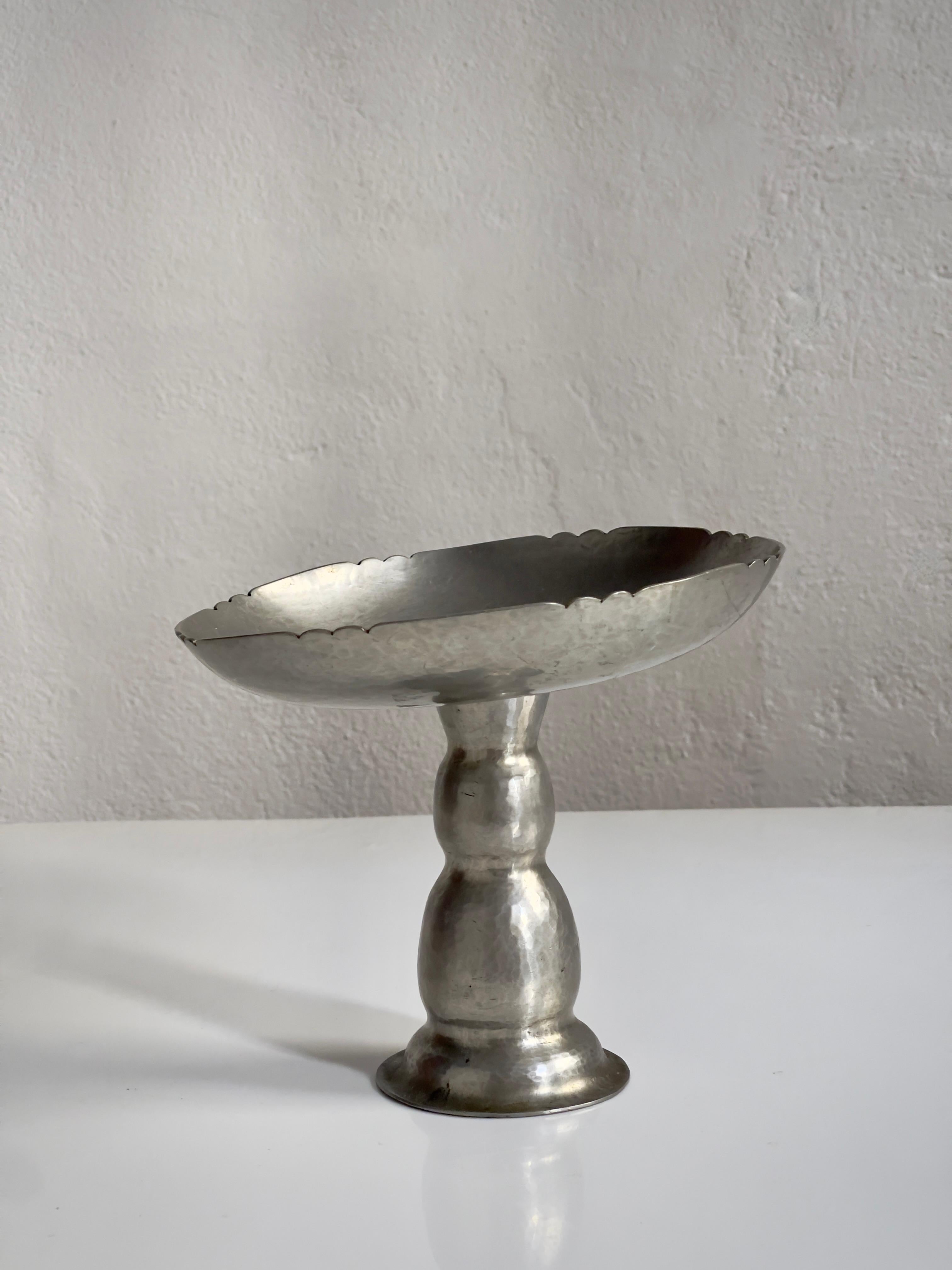 This elegant 1930s compote bowl, attributed to the esteemed Danish sculptor and metalworker Just Andersen, exemplifies the refined craftsmanship and sculptural integrity that define early 20th-century Scandinavian metalwork. Crafted in hammered
