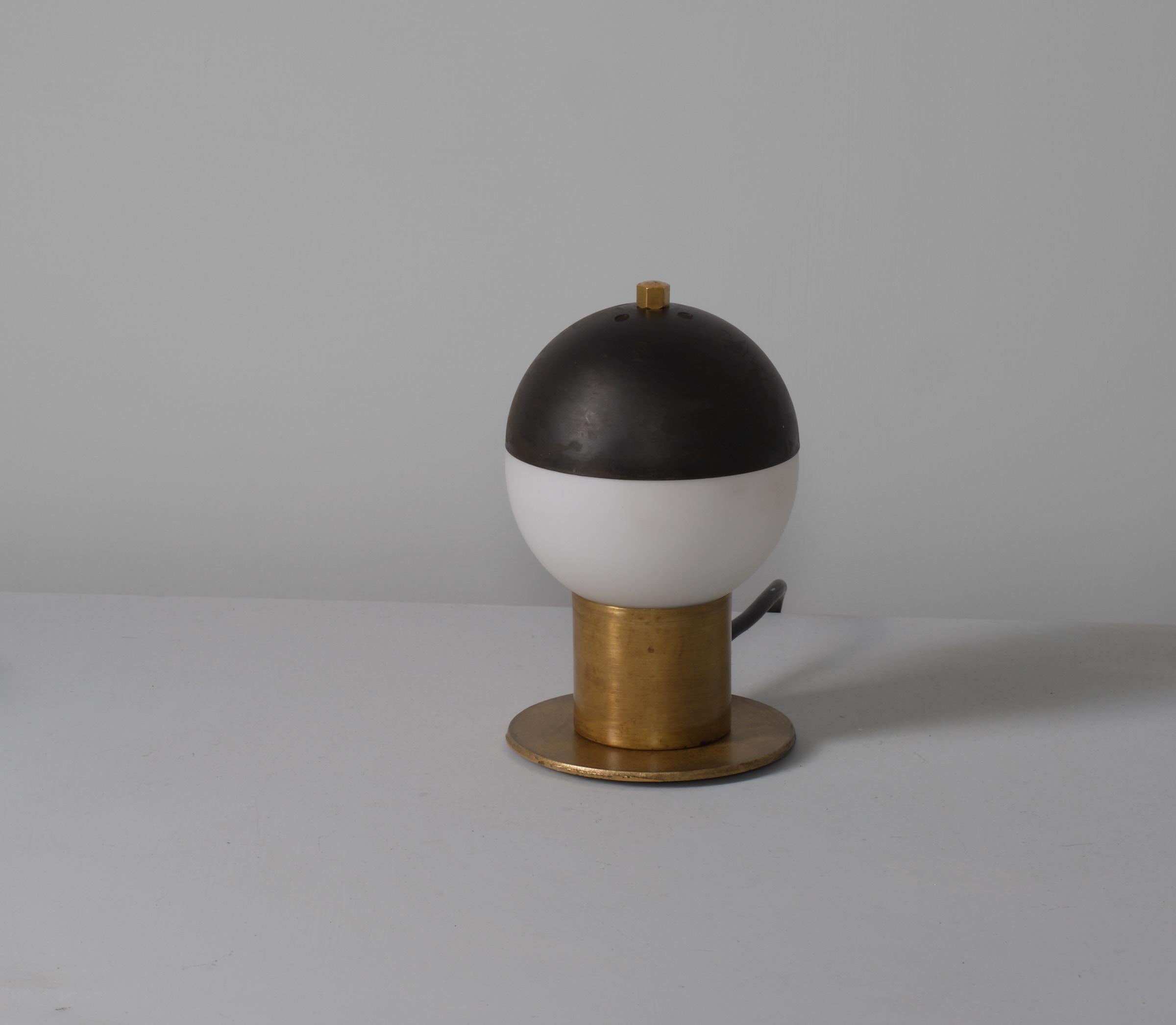 Classic Italian brass table lamp from the 1950s, crowned with a sophisticated blackened steel dome. The lamp’s brass base features a distinctive patina that adds depth and character, while the modern-looking steel dome provides a striking aesthetic