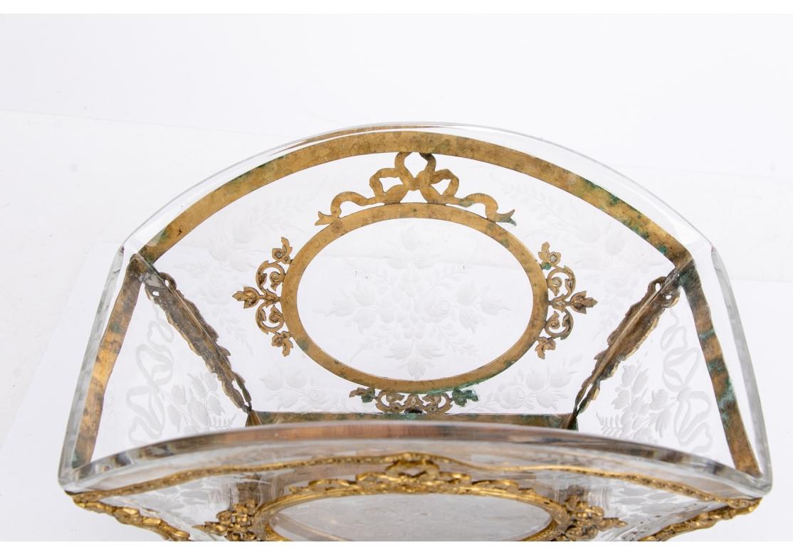 A flared rectangular bowl with etched crystal medallions decorated with roses and flowers on the long sides, and roses and bows on the ends. With elaborate elegant dore mounts with leafy bands and ribbon twist bands with flowers. The corners with