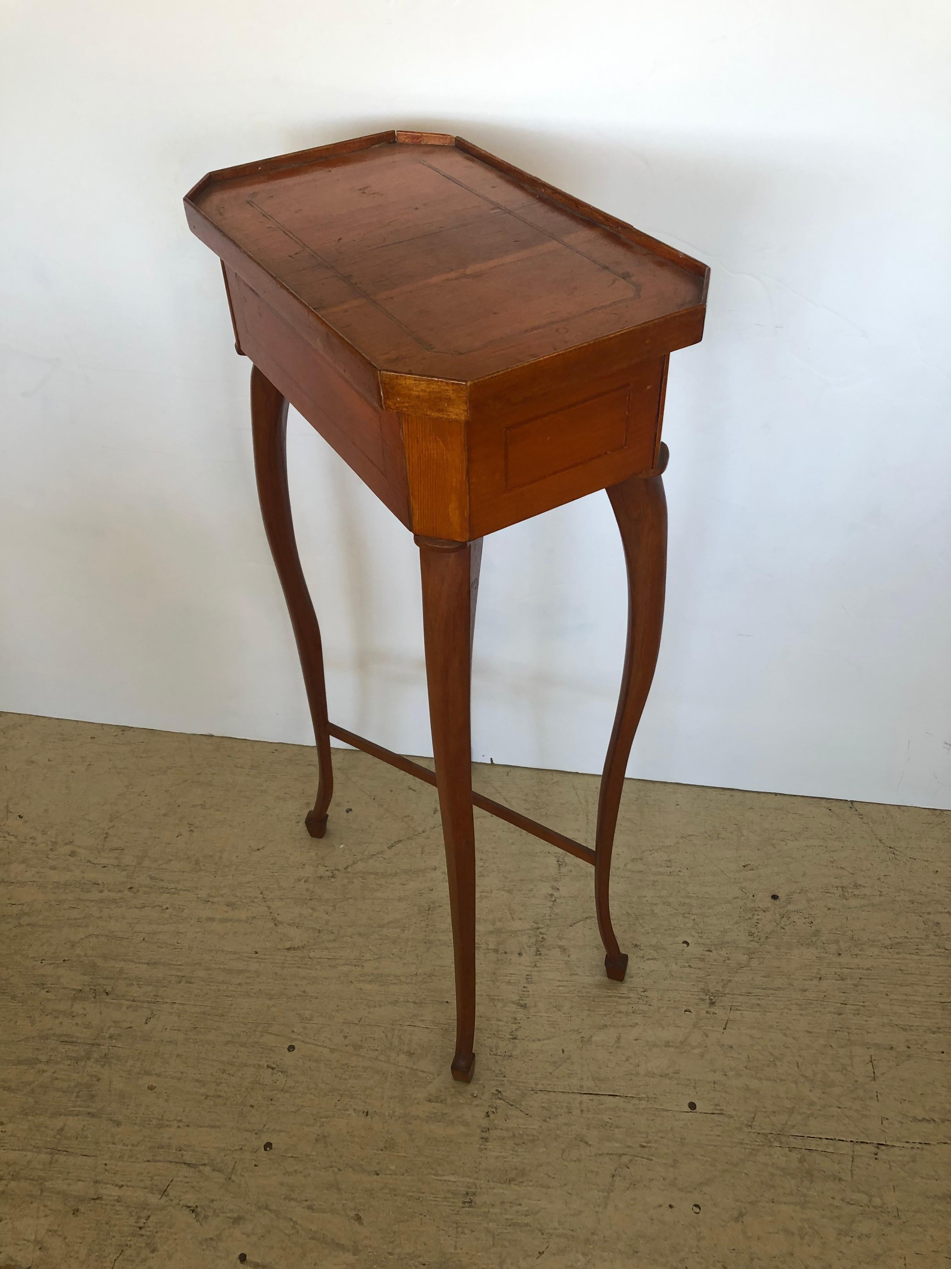 Authentic antique Biedermeier side table or stand having elegant fine silhouette, rectangular top with shallow gallery and angled edges, simple refined inlaid detail on top and apron, and slightly curved cabriole legs.