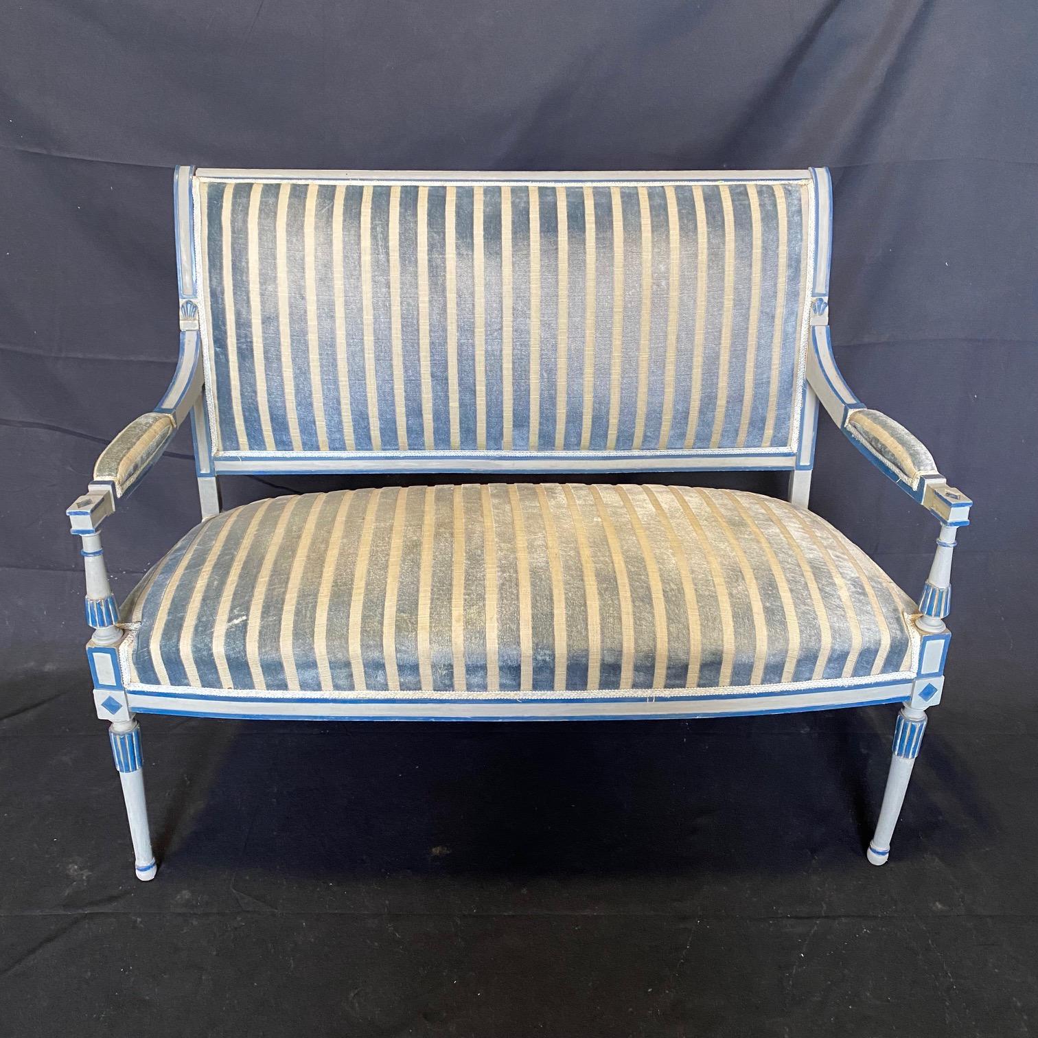 Sumptuous Belle Louis XVI style carved three-piece salon or parlor set, including a settee and two armchairs, all upholstered in a lovely blue gray fabric with raised velvet stripes. Original paint. 
Measures: Chair H 35.5