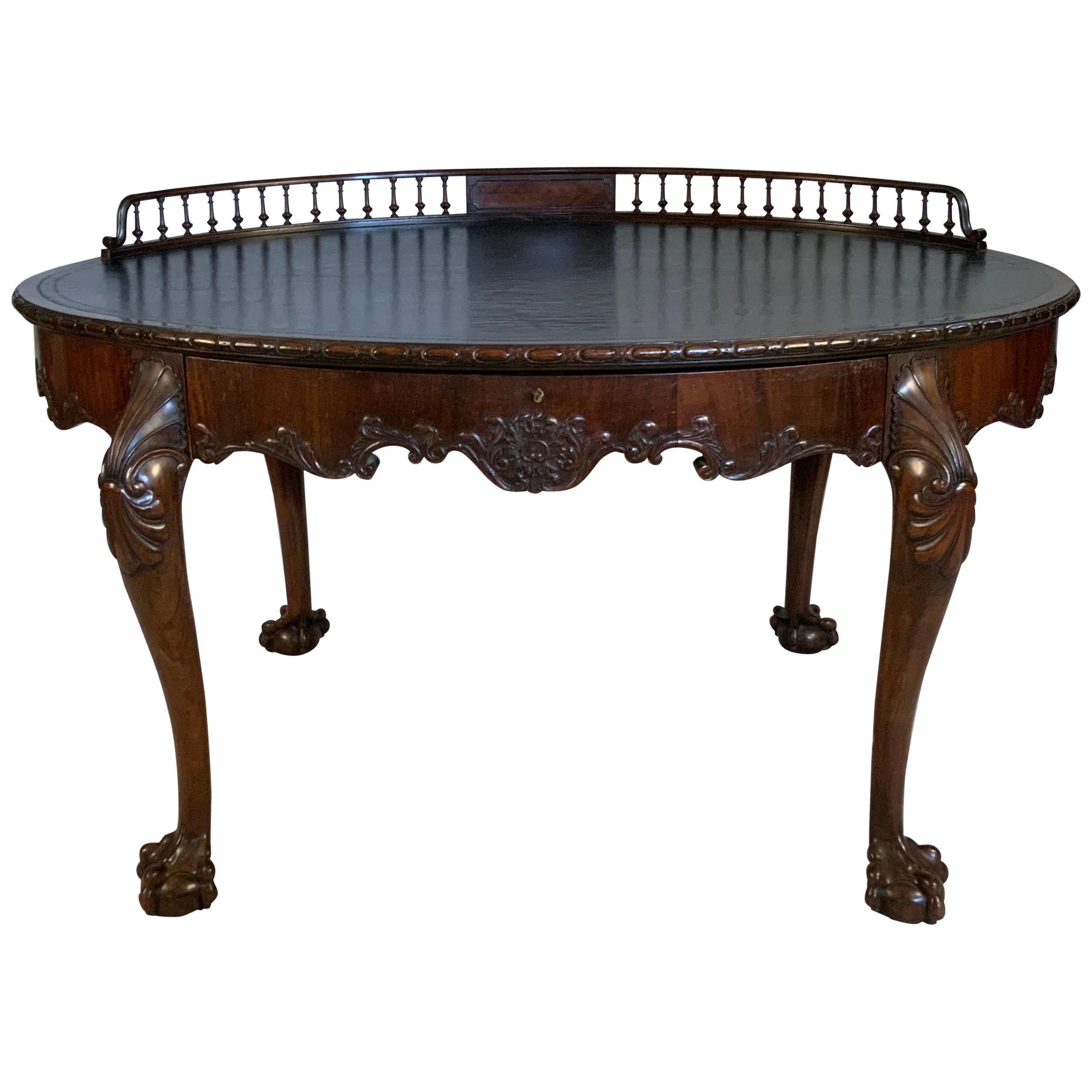 A beautiful mid-19th century English oval writing desk, with nicely carved ball and claw feet, a leather top with subtle greek key pattern around the edge, and a lovely gallery rail around the back. a single wide drawer in the front, with its