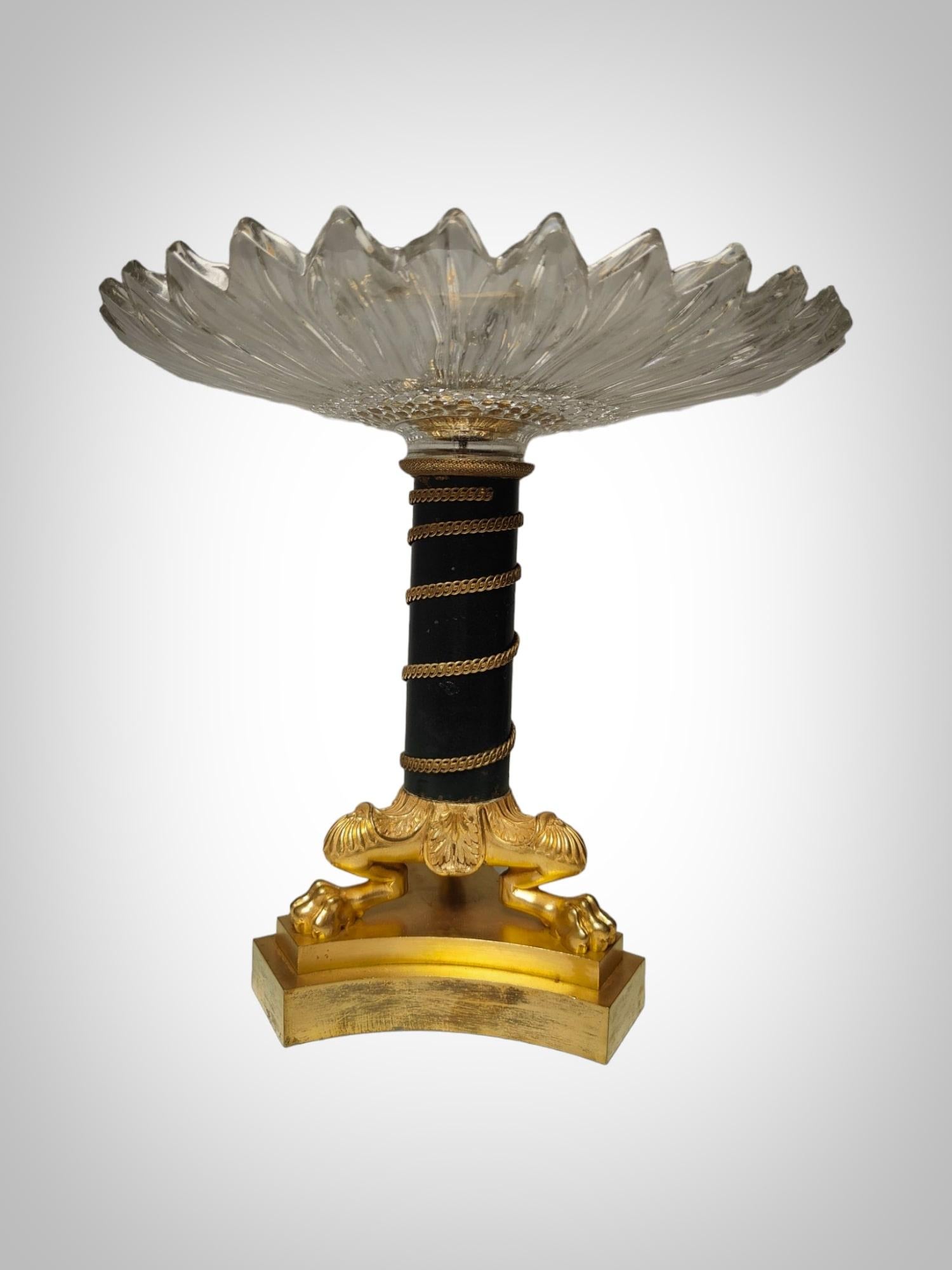 This exquisite centerpiece is a testament to the fine craftsmanship of 19th-century France. Crafted from gilded bronze and crystal, it exudes an air of timeless sophistication. The delicate interplay between the lustrous bronze and pristine crystal