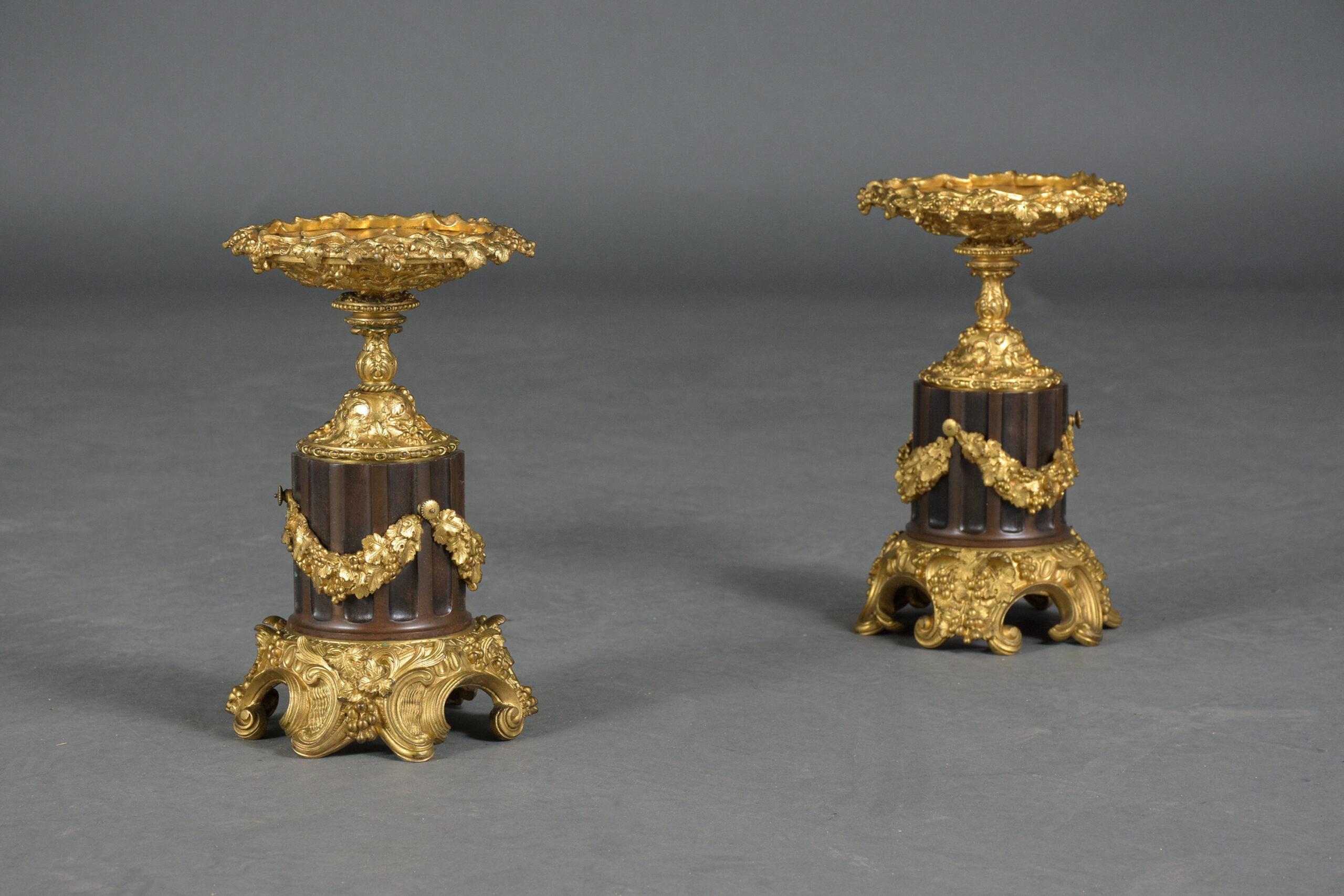 Step into the world of classical elegance with our exquisite pair of early 19th-century French urns, true masterpieces of craftsmanship and historical beauty. These antique cassolettes, crafted from bronzed material, have undergone professional