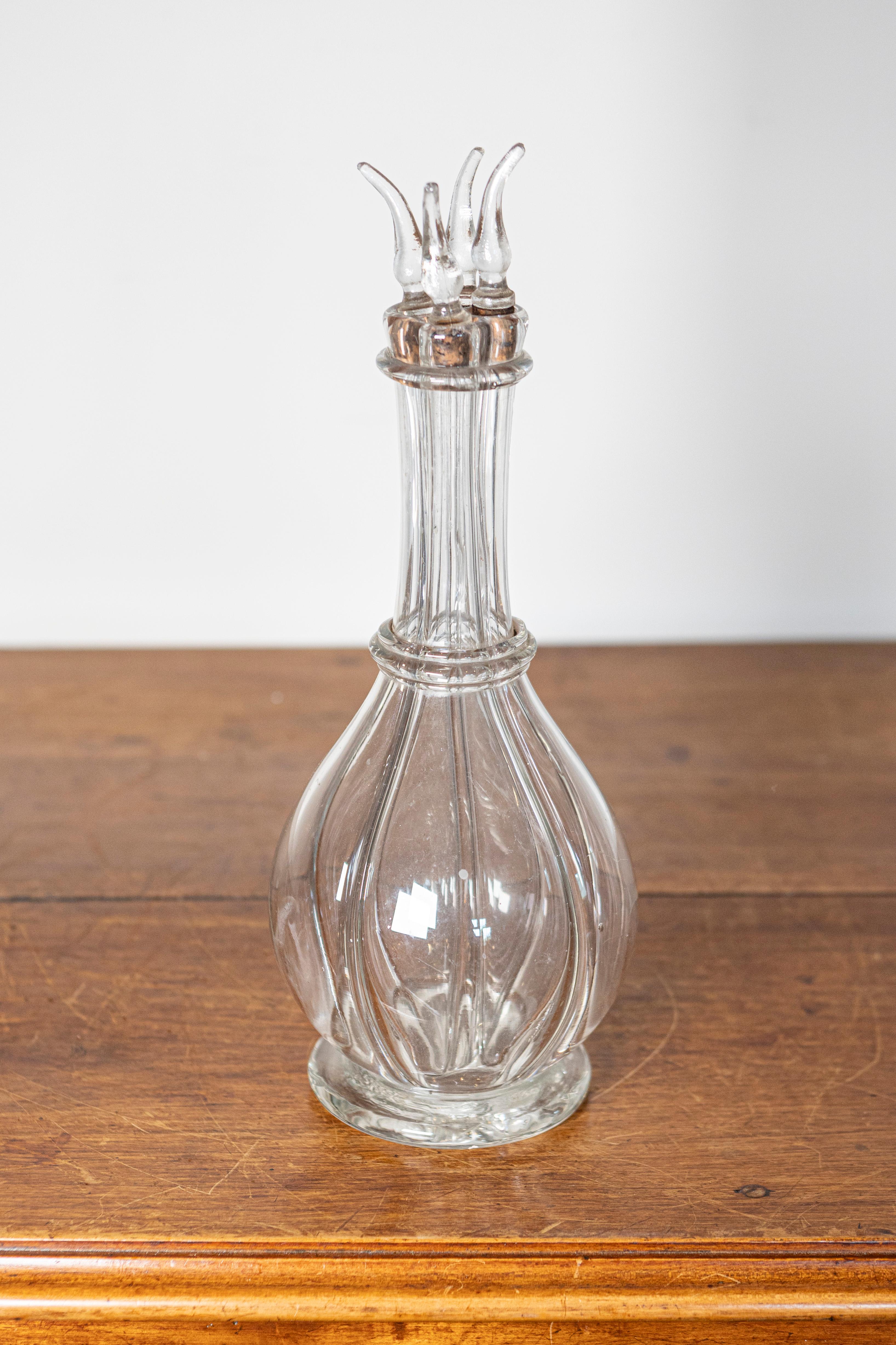 Cette exquise carafe en cristal français du XIXe siècle est un remarquable exemple de l'artisanat du verre, avec un corps gracieusement nervuré et un bouchon sculptural frappant rappelant des flammes délicates ou des pétales en fleurs. L'élégant col