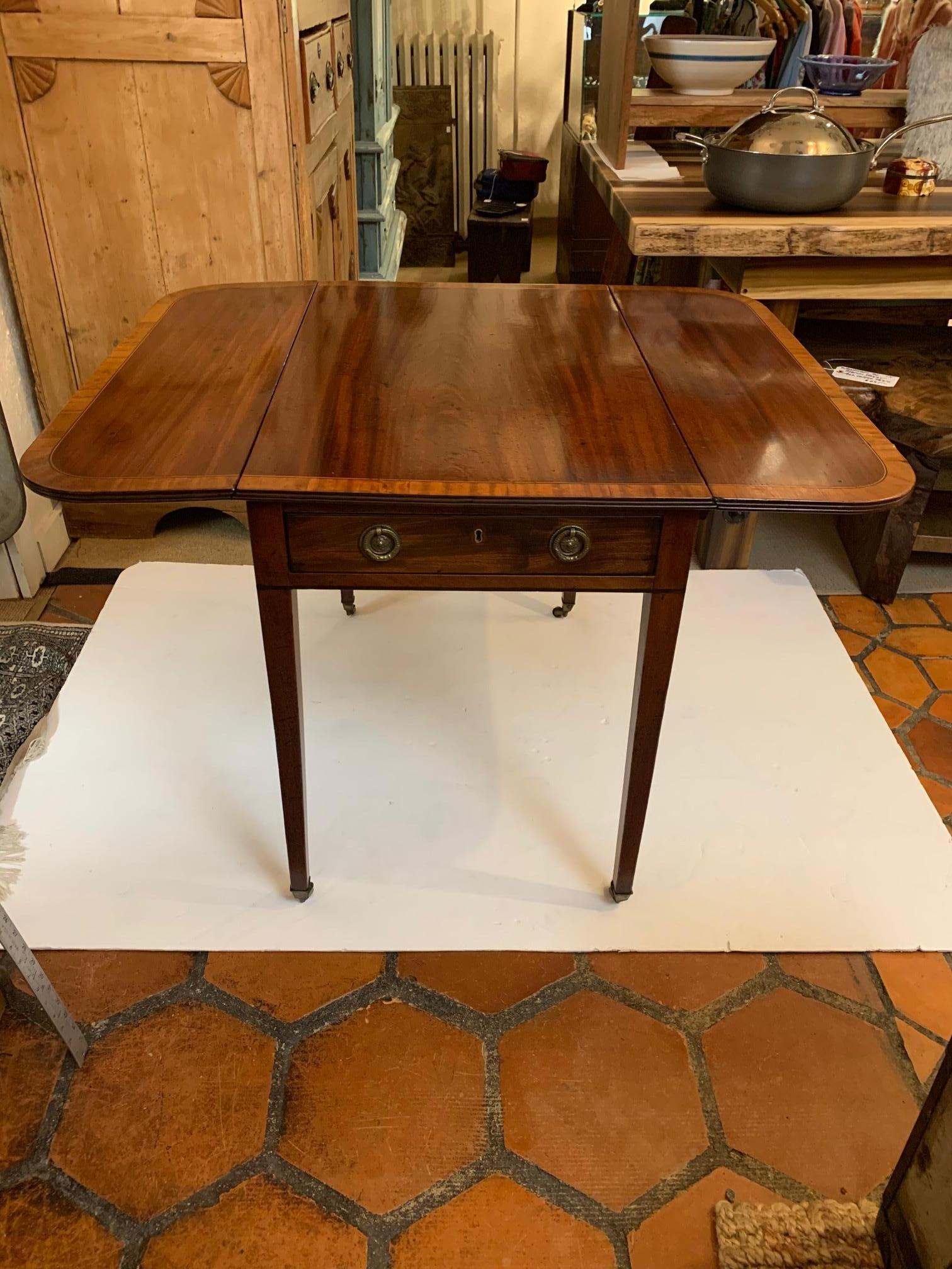 Magnificent antique English Pembroke mahogany and satinwood inlay table having one drawer, original hardware and brass casters on tapered legs.

Fully open 40” wide.