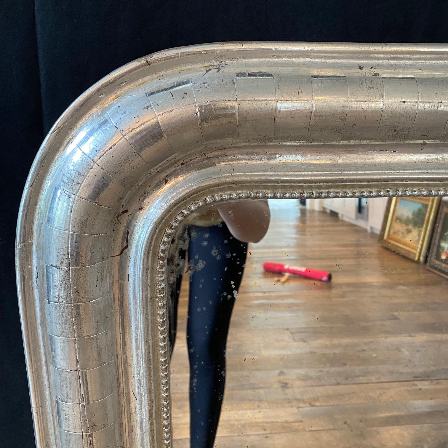 Silver leaf antique Louis Philippe mirror having a lovely striped pattern with beaded edge and curved top. Original pine board back. Circa 1880. Measures: Mirror itself is 22 W x 31.5 H
#6247.