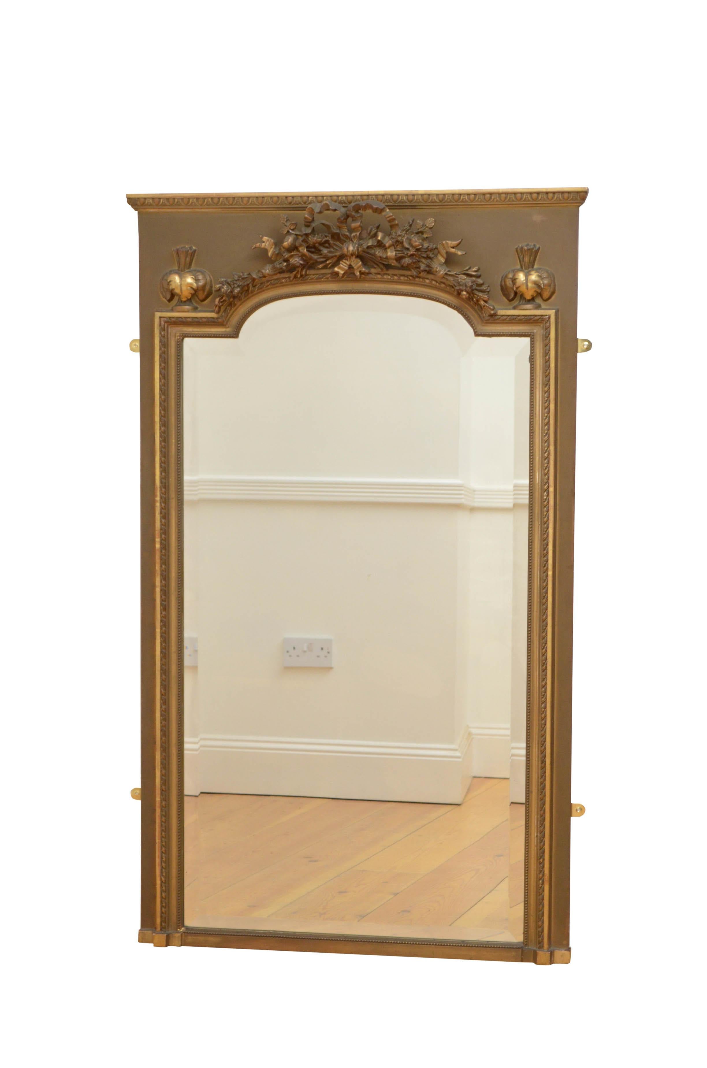 Beautiful French trumeau mirror with original beveled edge glass with some foxing in gilded, beaded and carved frame with egg and dart cornice and foliage centre crest with a bow flanked by leafy finials, all on dark green frame. This antique mirror