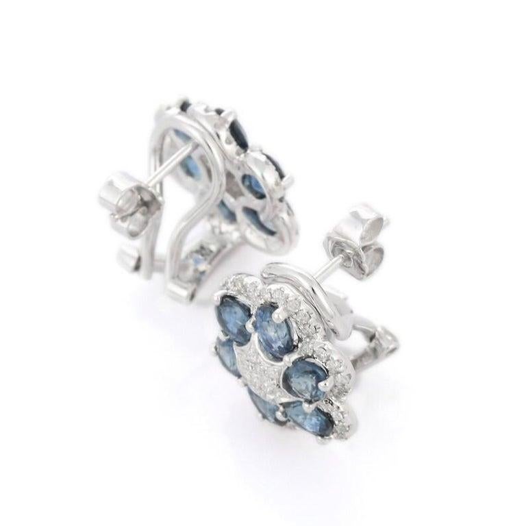 Questi eleganti orecchini a perno floreali sono splendidamente realizzati in oro bianco 14 carati e mostrano un'armoniosa miscela di vibranti gemme blu e diamanti abbaglianti. Gli orecchini presentano 2,81 carati di pietre blu vivaci, disposte in un