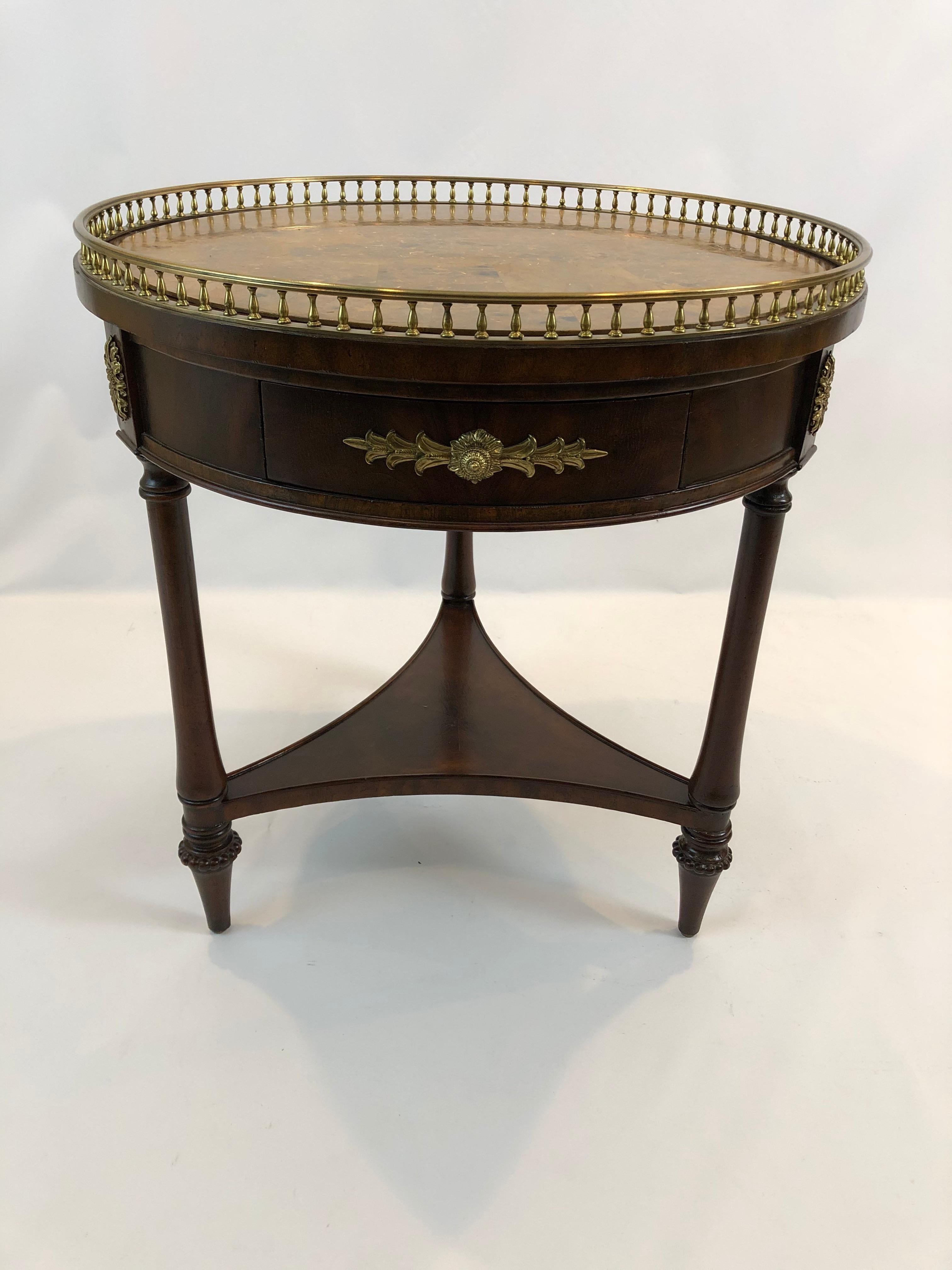 Stunning round mahogany side table by Maitland Smith having handsome caramel faux marble top with lovely brass gallery and 3 drawers around the periphery and beautiful ornate brass hardware. There are other beautiful details such as brass mounts on