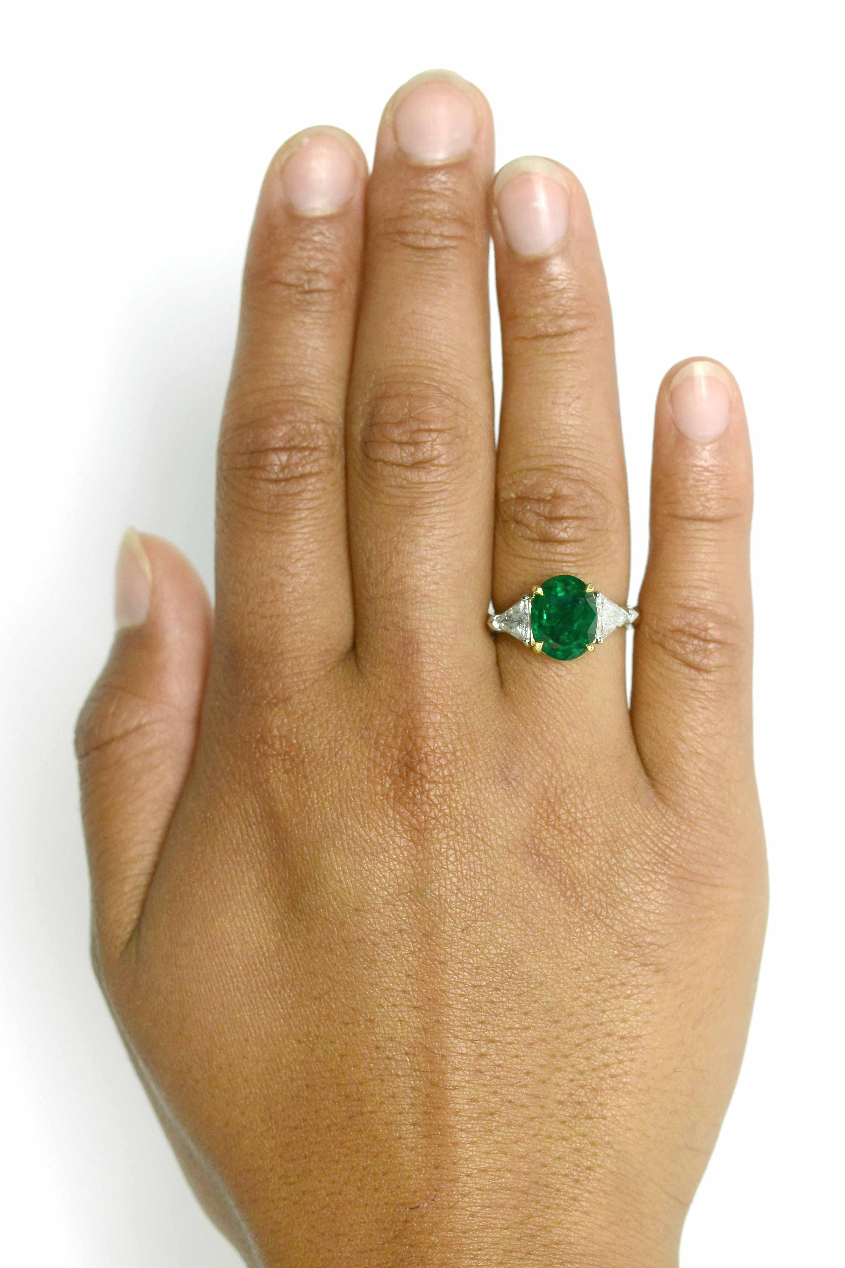 A most elegant emerald engagement ring composed as a classic, timeless 3 stone trinity. Centered by a lustrous, vibrant rich green natural emerald that glows with a fire within it's soul. Weighing 3.74 carats and smartly flanked by a pair of