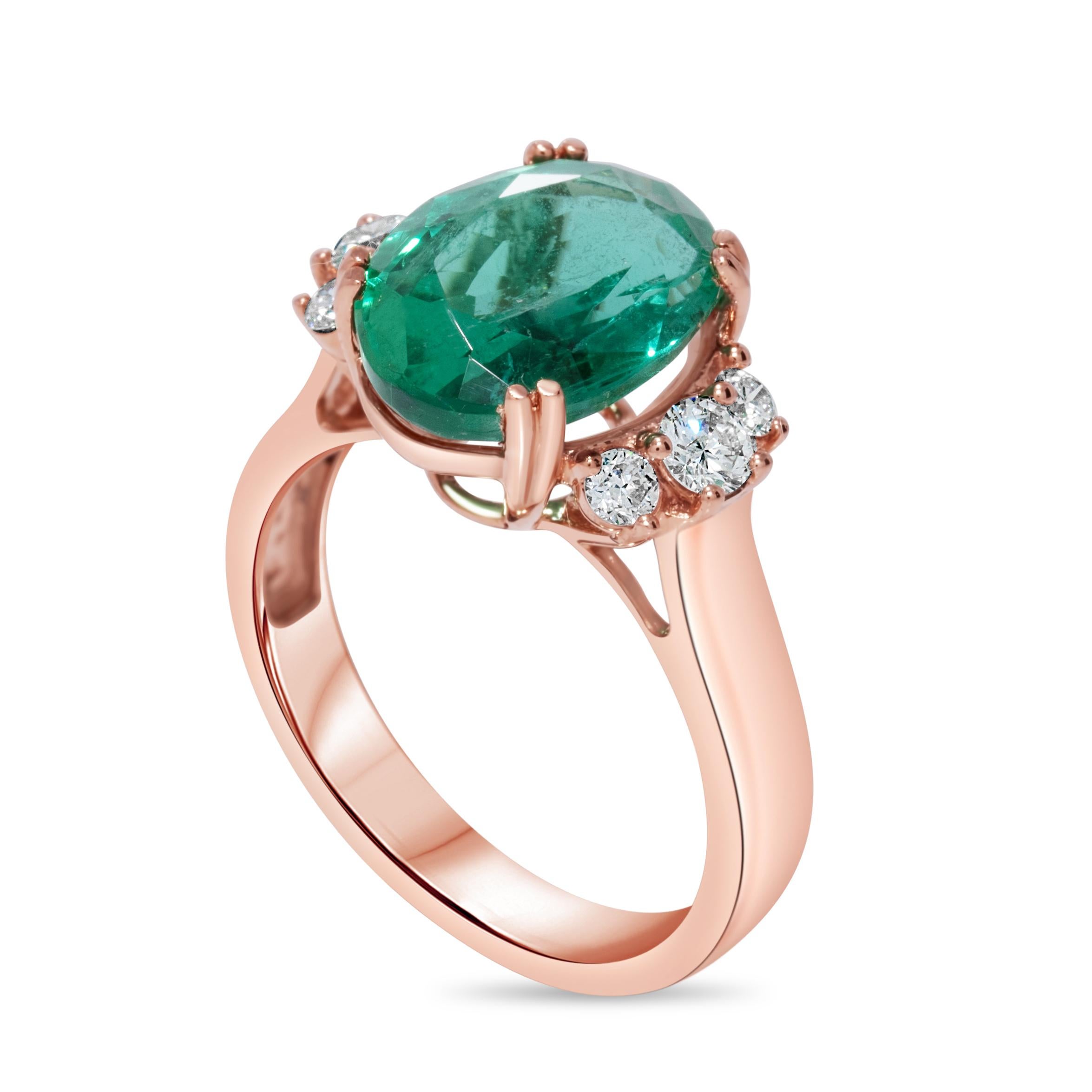 A beautiful fashion ring made from 14k rose gold featuring an oval-shaped emerald weighing 4.10 carats. The emerald is accented by 6 round green diamonds, totaling 0.38 carats. The rose gold setting adds a warm, romantic tone that complements the