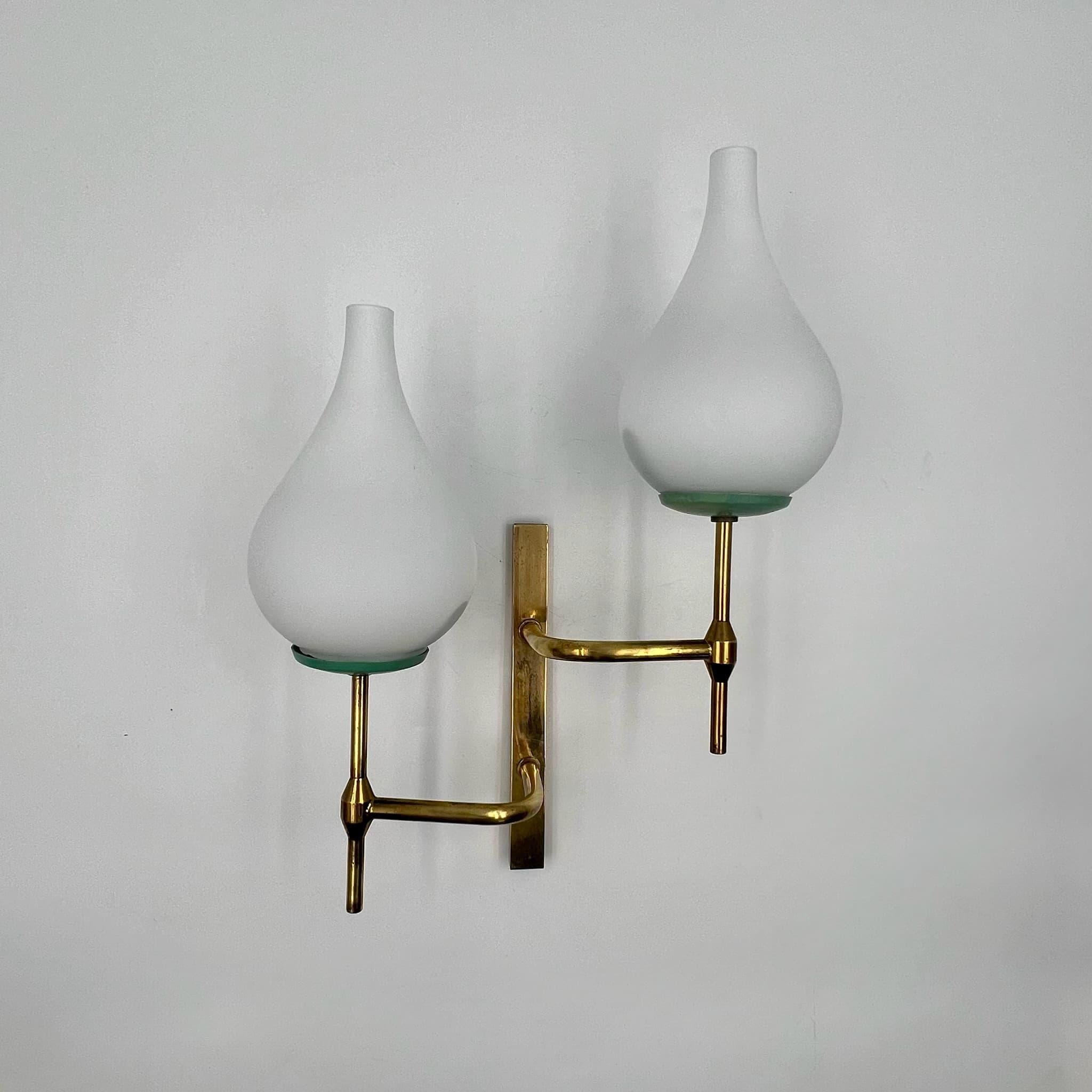 Illuminate your space with mid-century charm using this exquisite Stilnovo-inspired vintage 50s lamp crafted in Italy. Made from brass and opaline glass, this wall light epitomizes the sophistication and craftsmanship synonymous with the Stilnovo