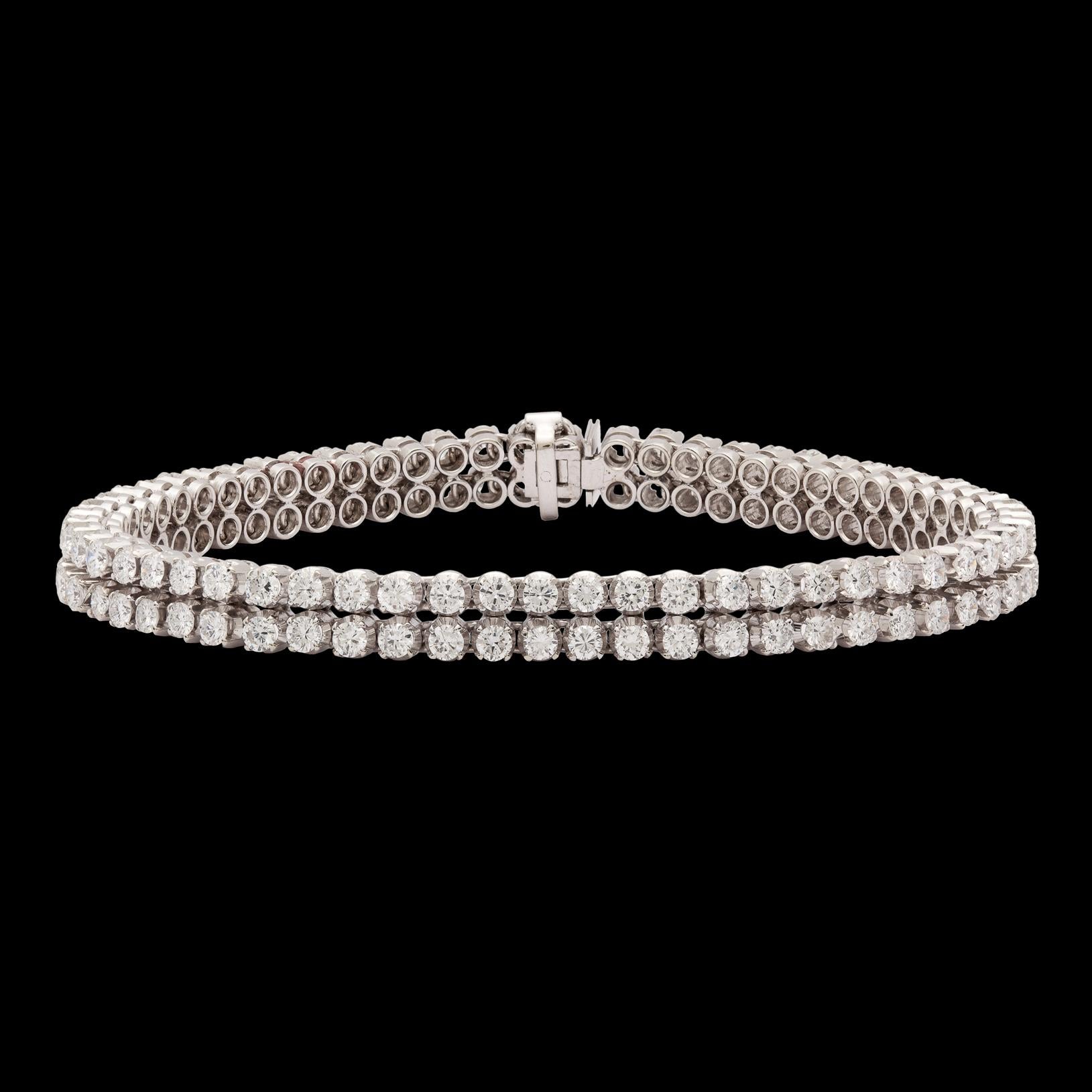 Double the sparkle of a traditional diamond line bracelet. This 18kt White Gold Double Row Diamond Tennis Bracelet totals 6.70 carats, linking two diamond tennis bracelets together for one impressive look. The bracelet measures 7 inches long and