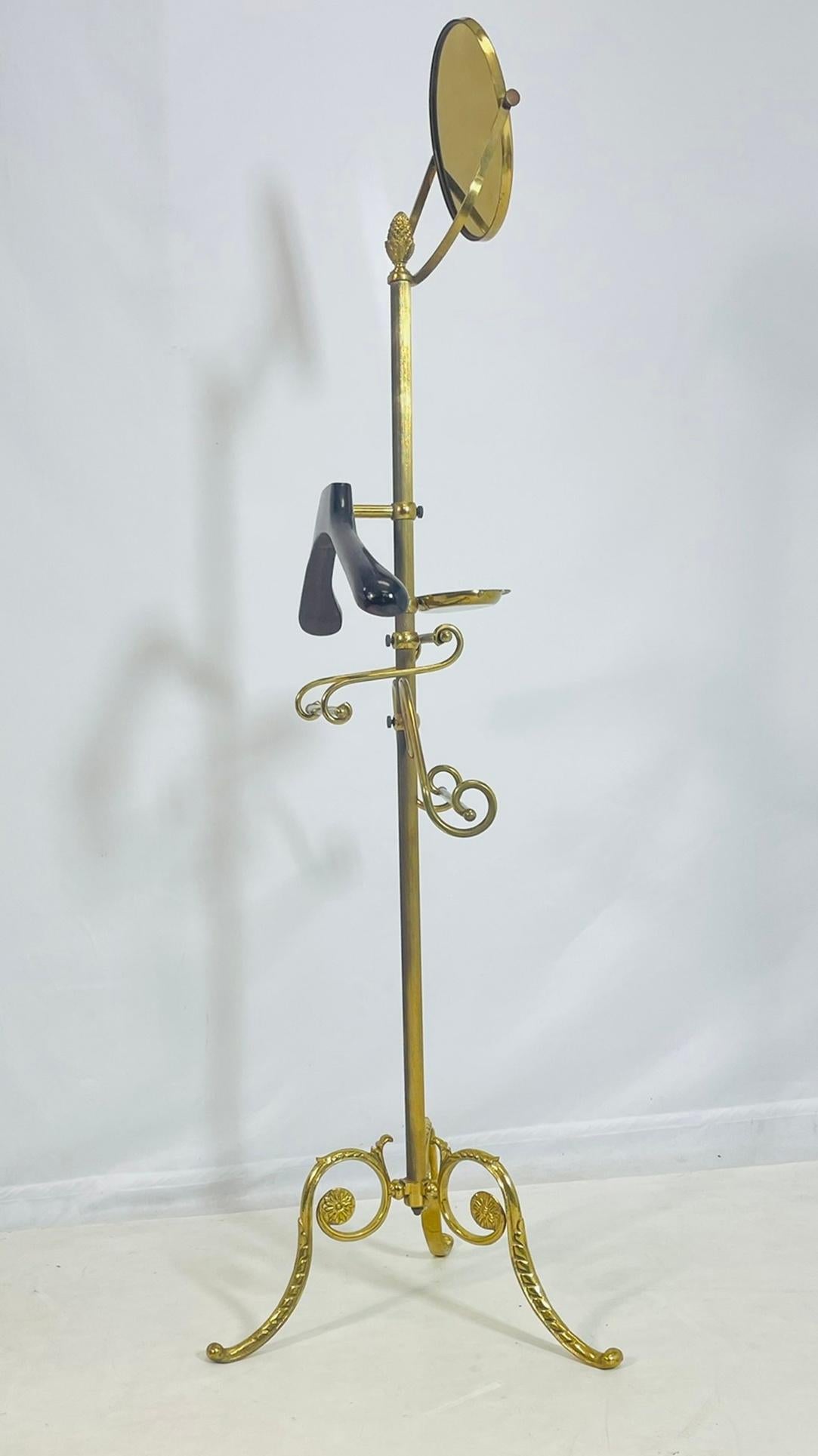 Elegante e finemente lavorato, il portavalori in ottone presenta uno specchio ovale girevole, una ricca decorazione a volute e una base a treppiede con accenti di rosette. Questo pezzo sorprendente unisce funzionalità e fascino decorativo, forse di