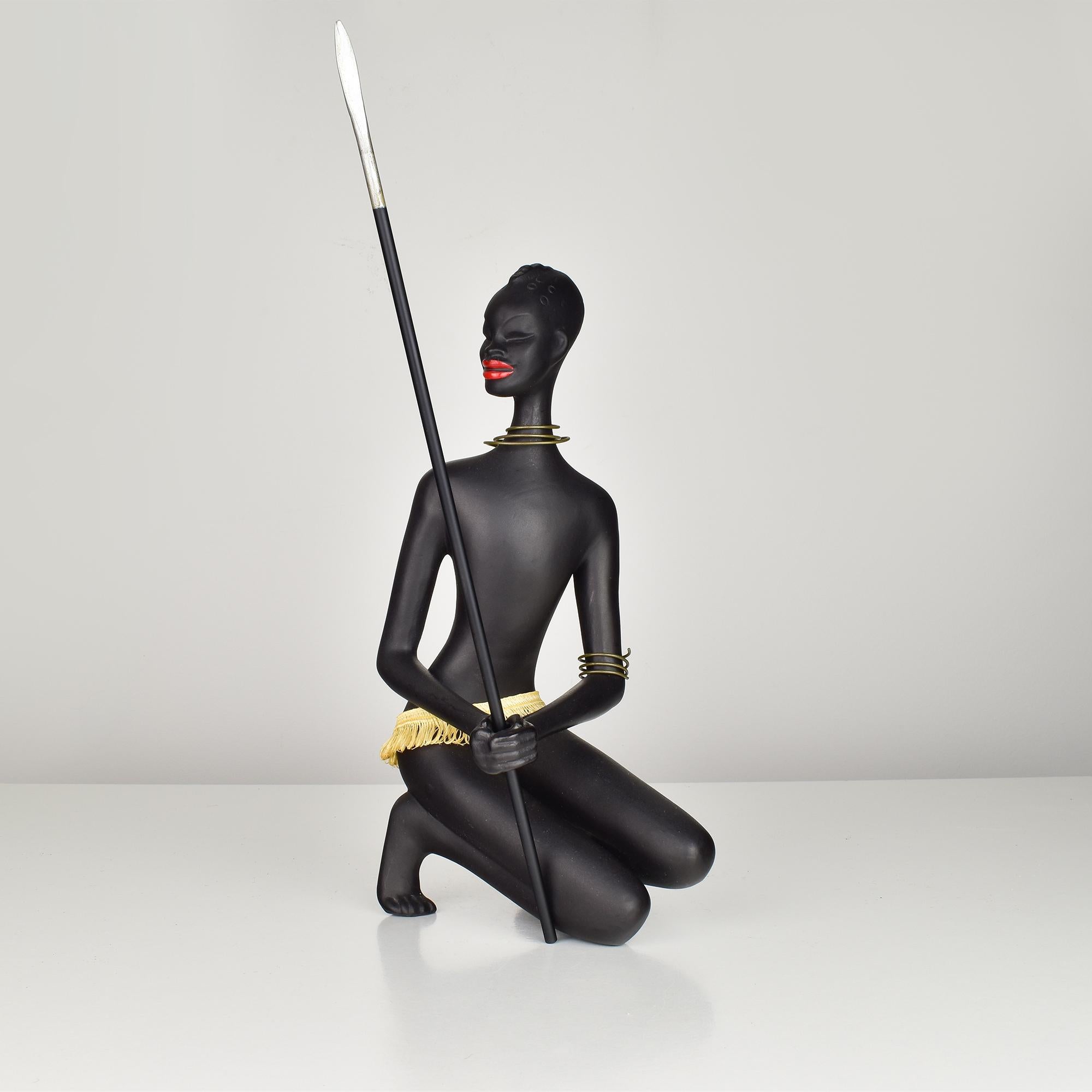 Diese auffällige Keramikfigur stellt einen afrikanischen Krieger dar, der in einer dynamischen knienden Position einen Speer mit einer Ausstrahlung von Stärke und Selbstvertrauen schwingt. Die Figur zeichnet sich durch ihre glatte, mattschwarze
