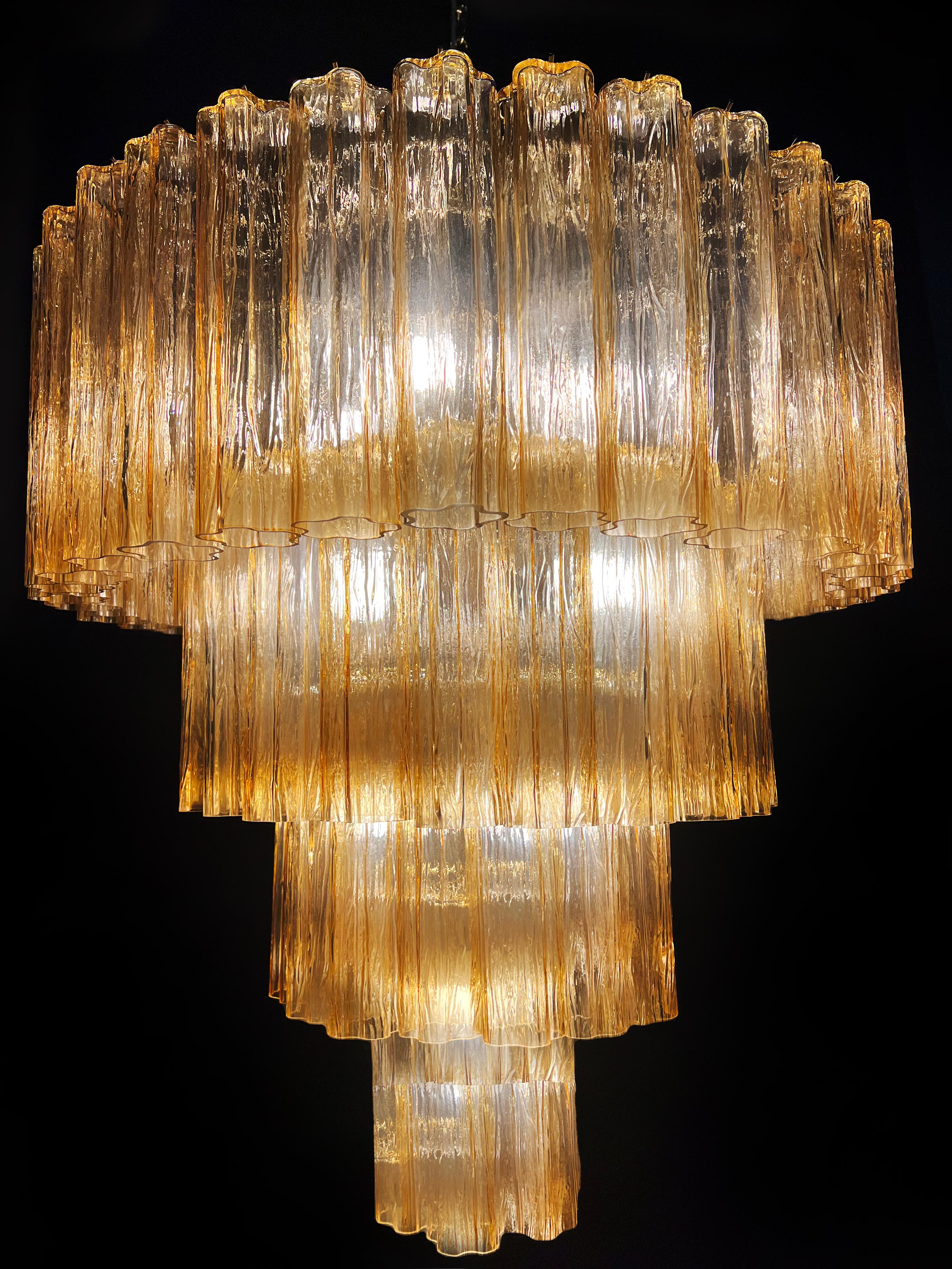 Elegante coppia di lampadari di murano. Il caldo colore ambrato vibra con le sfumature dell'oro, l'effetto è magnetico e sofisticato. L'altezza senza catena è di 112 cm. Può essere realizzato secondo le dimensioni richieste dal cliente.