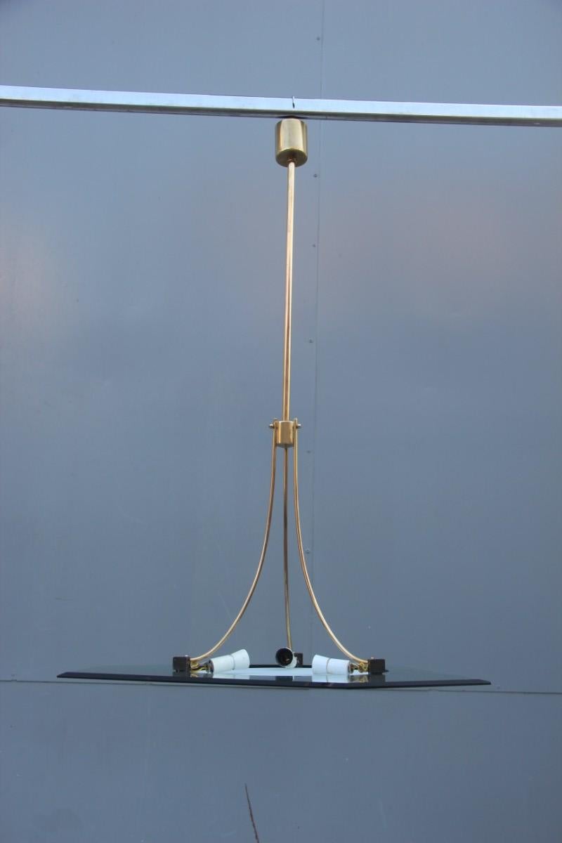 Elegante ed essenziale lampadario italiano del 1950, realizzato con una lastra di cristallo di colore verde, al centro un vetro smerigliato rotondo, il tutto trattenuto da una struttura in ottone, parti in ottone canna di fucile, che ricorda molto