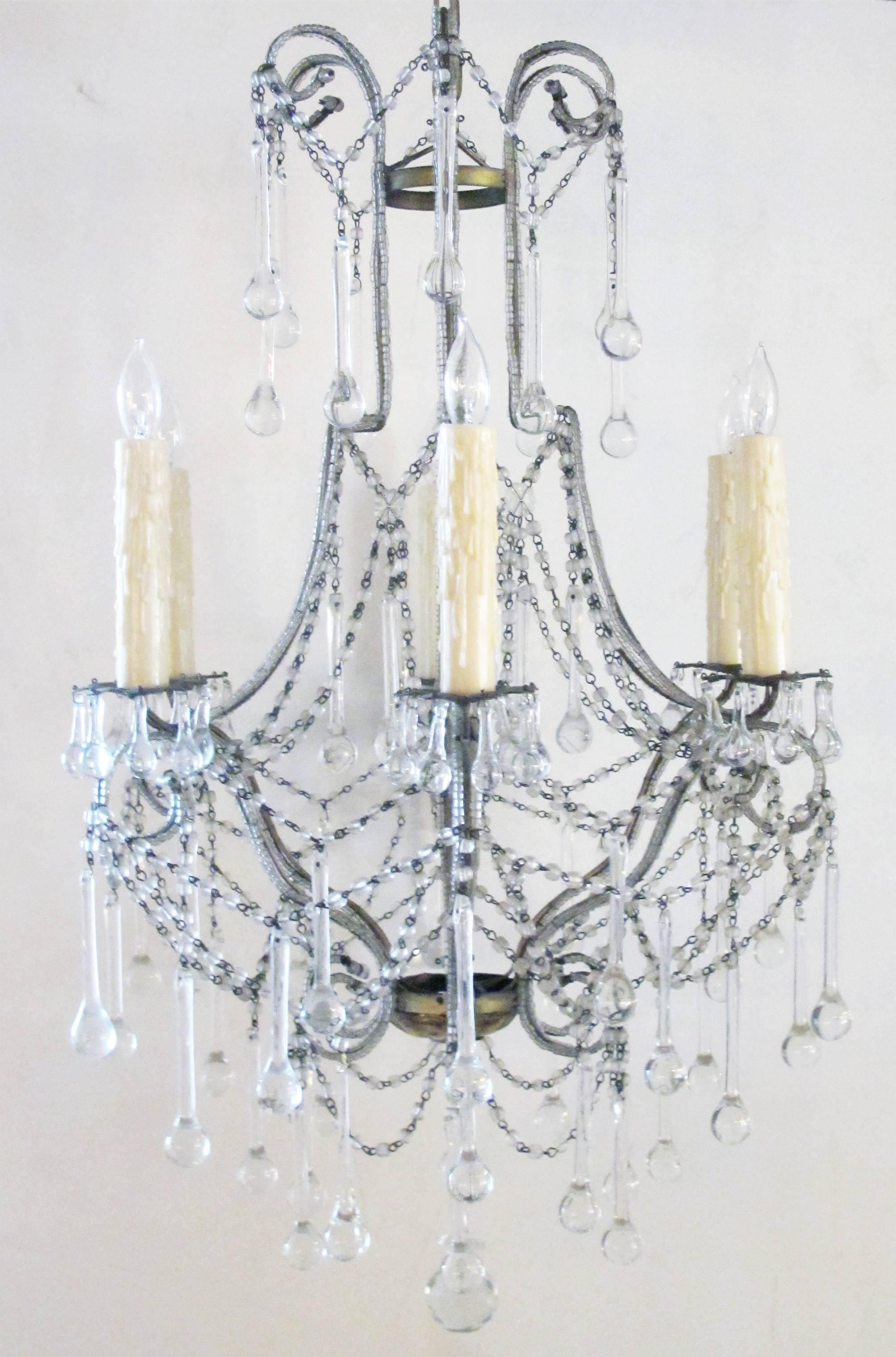 An elegant and graceful pair of Italian 1960s cage-frame beaded six-light chandeliers with tear drop crystal pendants; the beaded frame supporting six candle cups; adorned overall with graceful teardrop pendants.