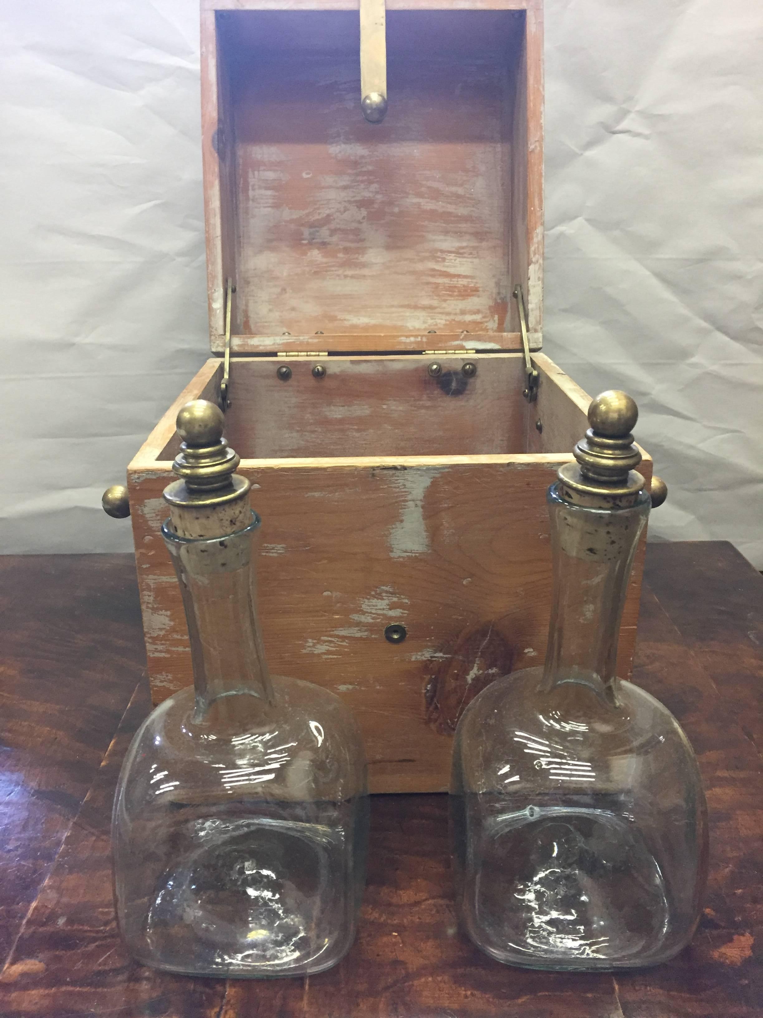 Wonderful distressed pickled wood spirits box with brass details having four handblown bottles inside topped with corks.