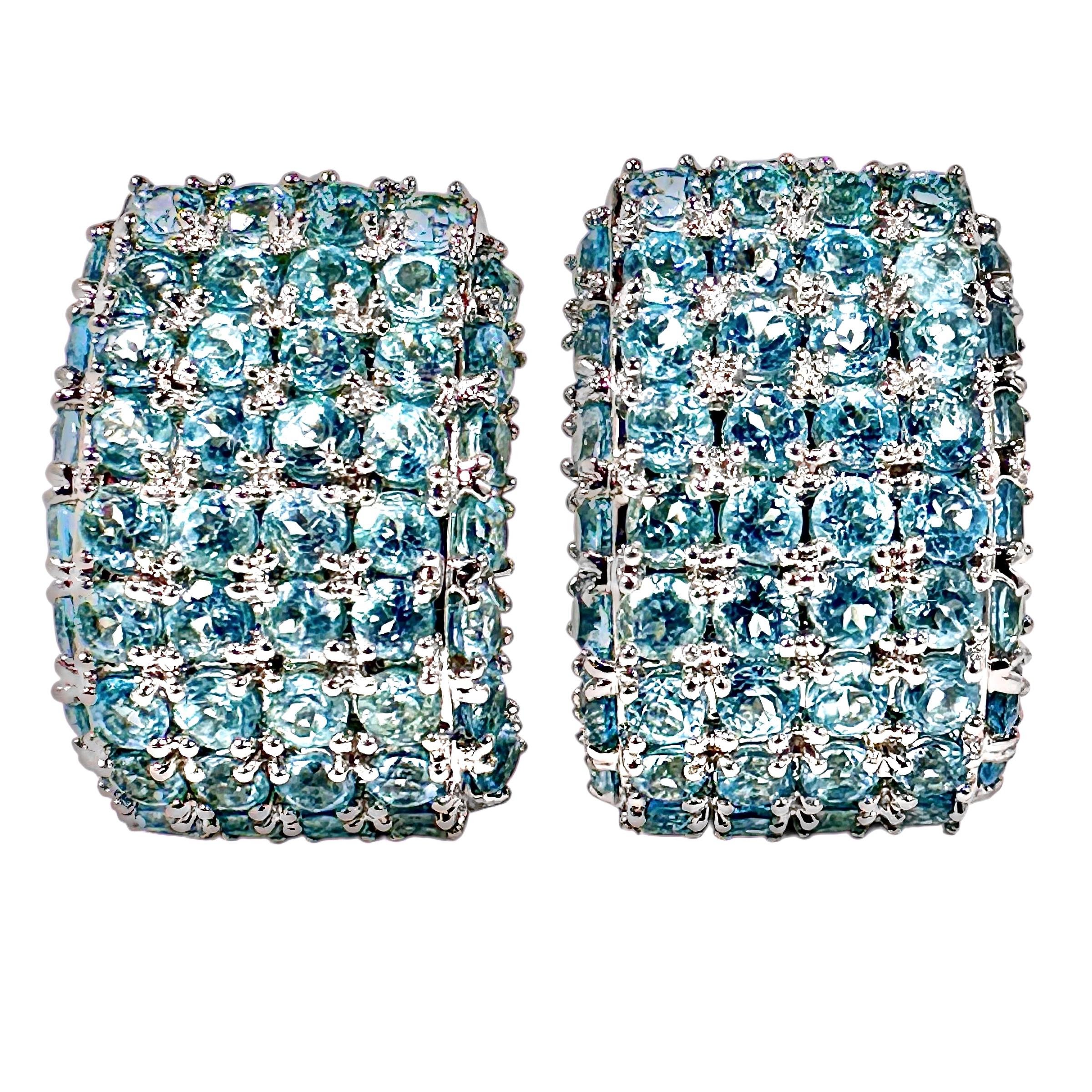 Cette ravissante paire de boucles d'oreilles contemporaines en or blanc 18 carats est sertie avec précision d'un total de 100 aigues-marines naturelles rondes à facettes d'un bleu éclatant. Les pierres sont serties sur le devant des boucles