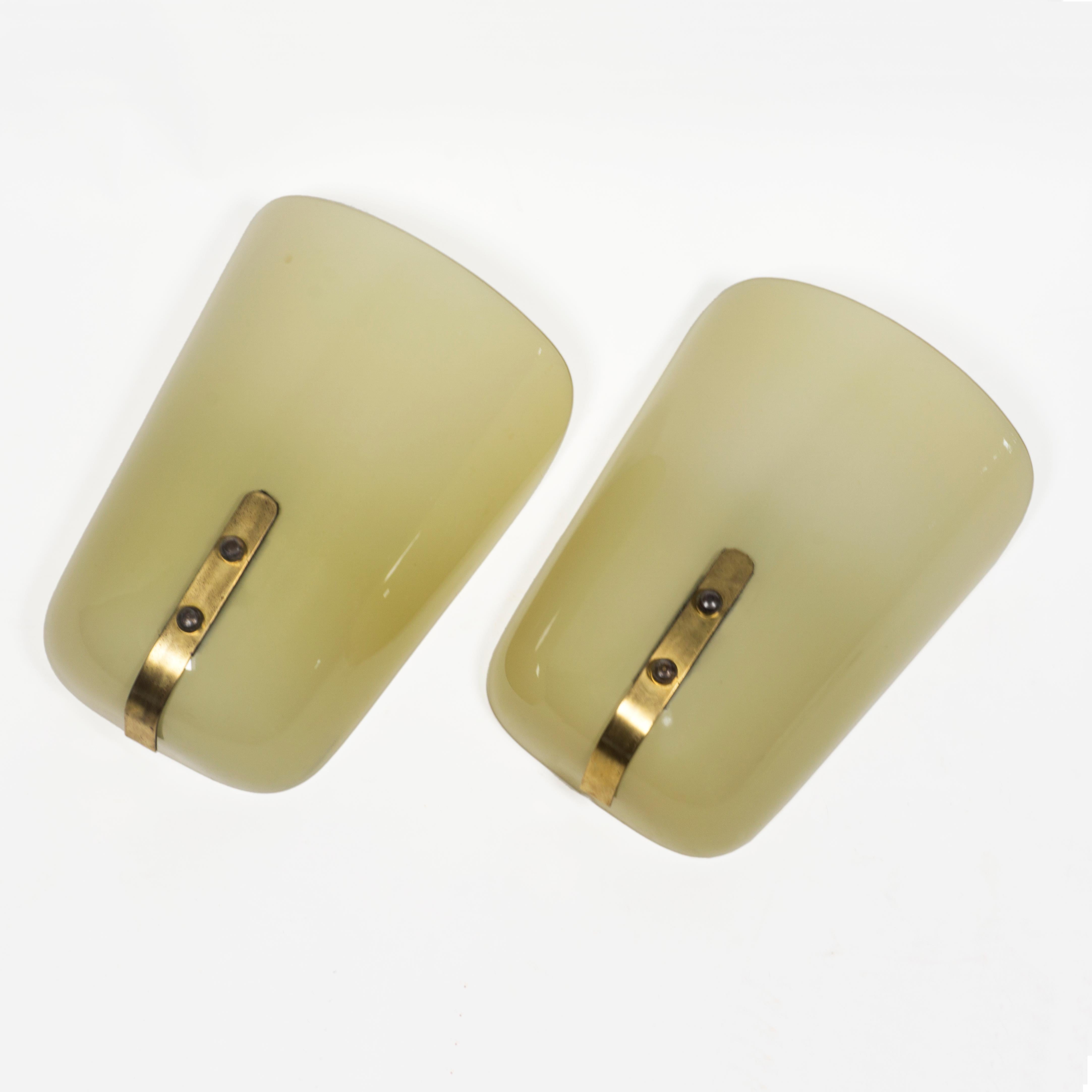 Very elegant pair of sconces from the Art Deco period. 
Each wall light has a large shade made of thick yellowish glass which is attached to the brass holder with two screws. Timeless design and high-quality workmanship.
These lamps produce a very
