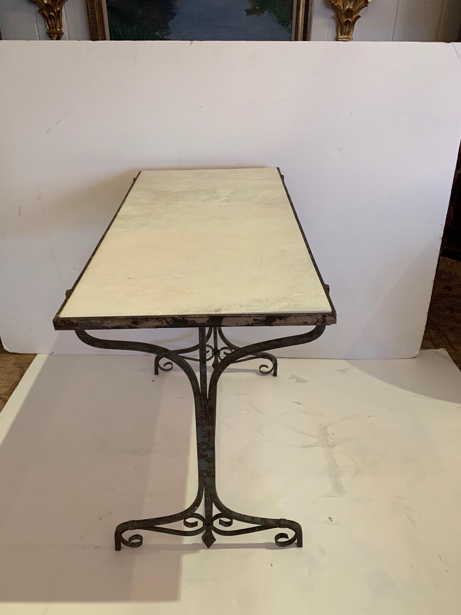 French style small bistro table or console having white marble top and elegant distressed iron base.