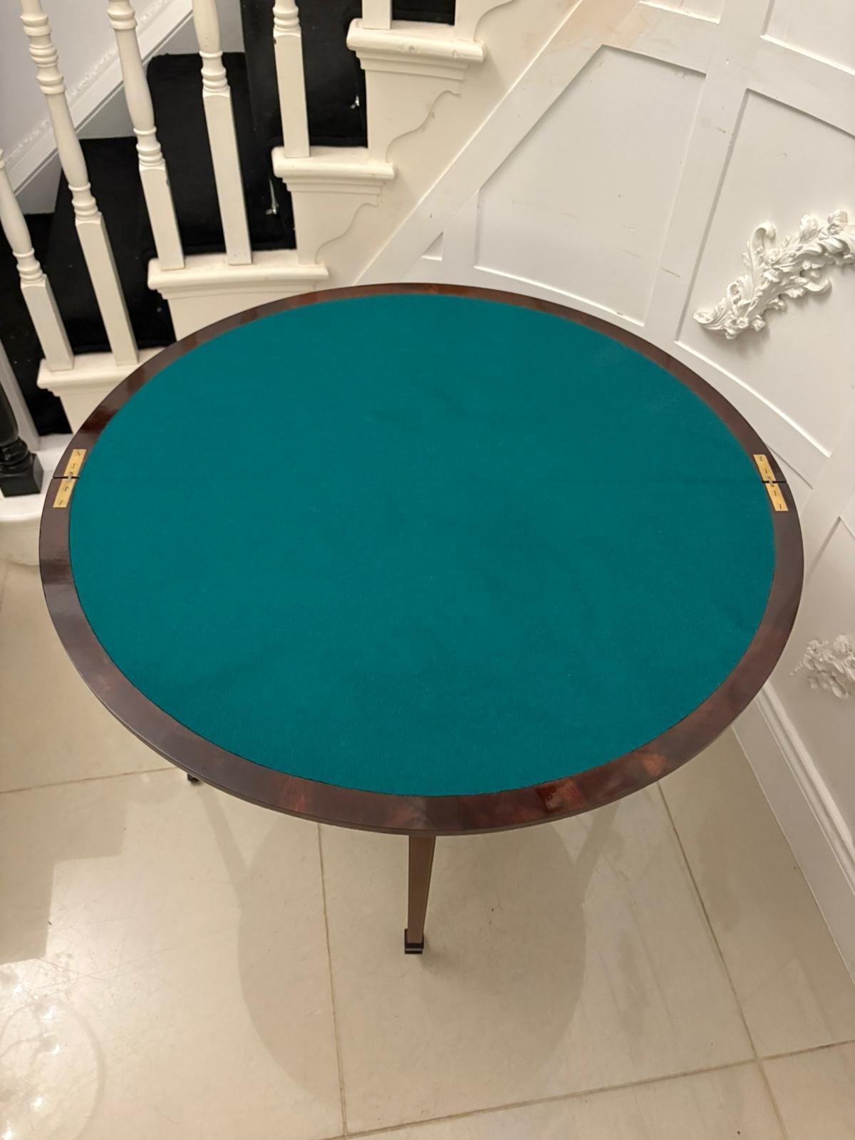 A fine late Victorian antique fold-over card table beautifully crafted in richly figured mahogany with delicate satinwood crossbanding and string inlay. The demi-lune top opens to form a circular baize-lined playing surface, supported by a swivel